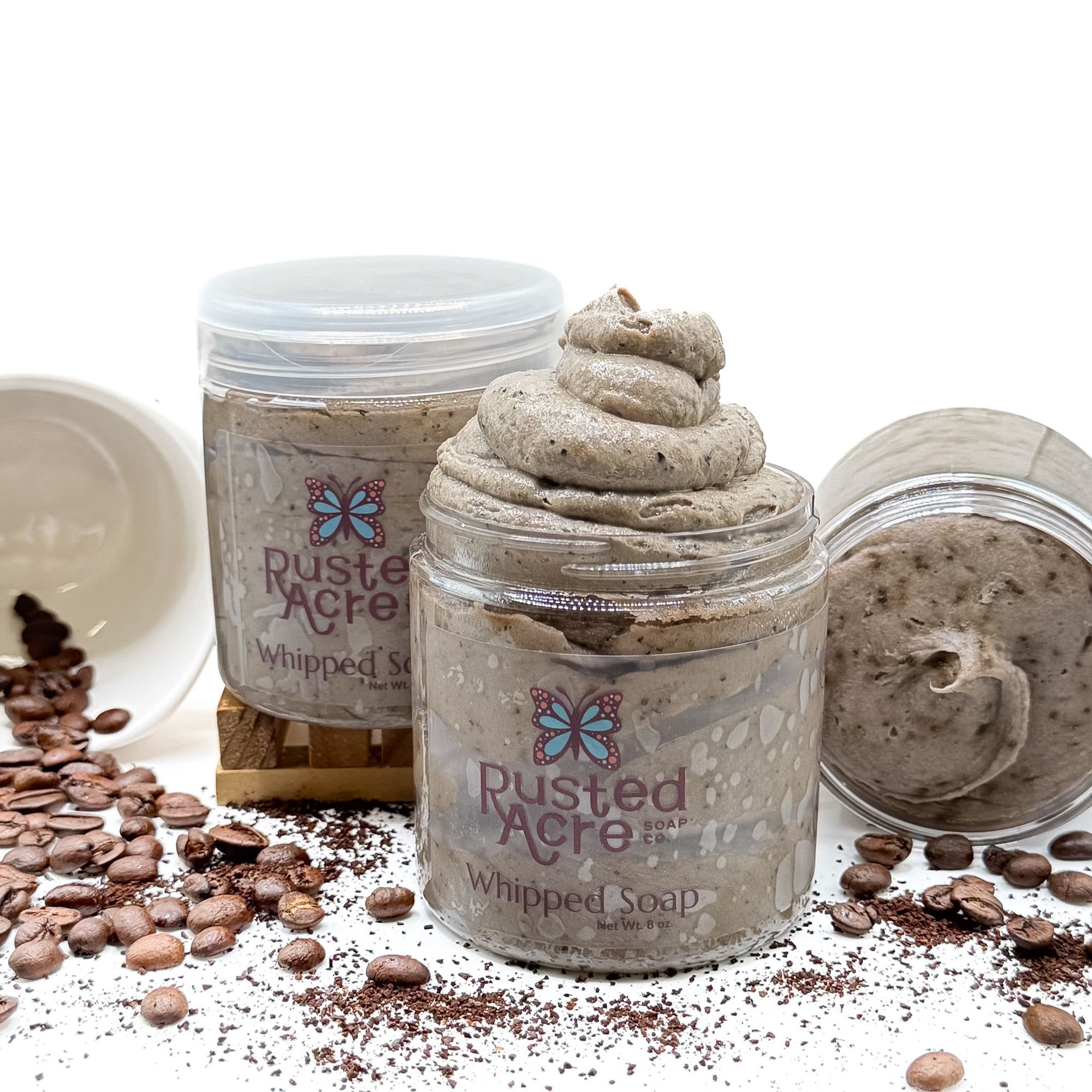 3 jars of Rusted Acre coffee whipped soap with coffee beans and a mug on a white background.