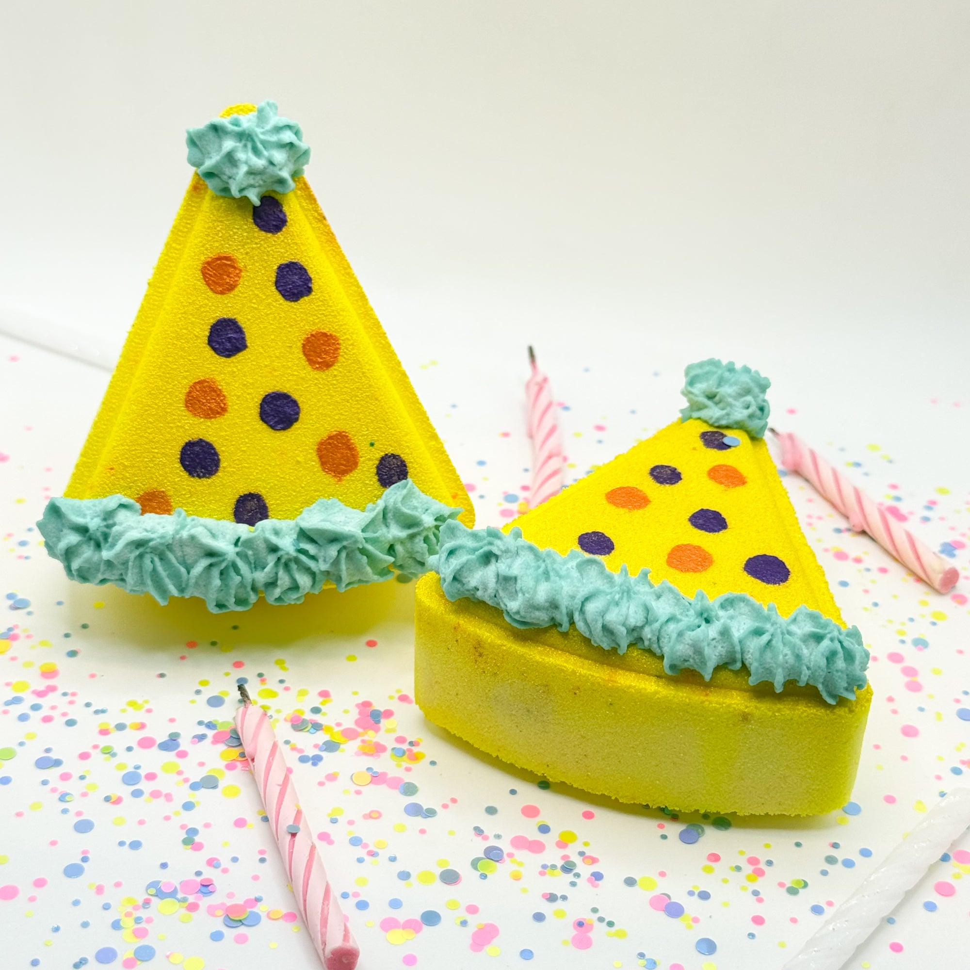 Two yellow birthday hat shaped bath bombs with hand painted polka dots.