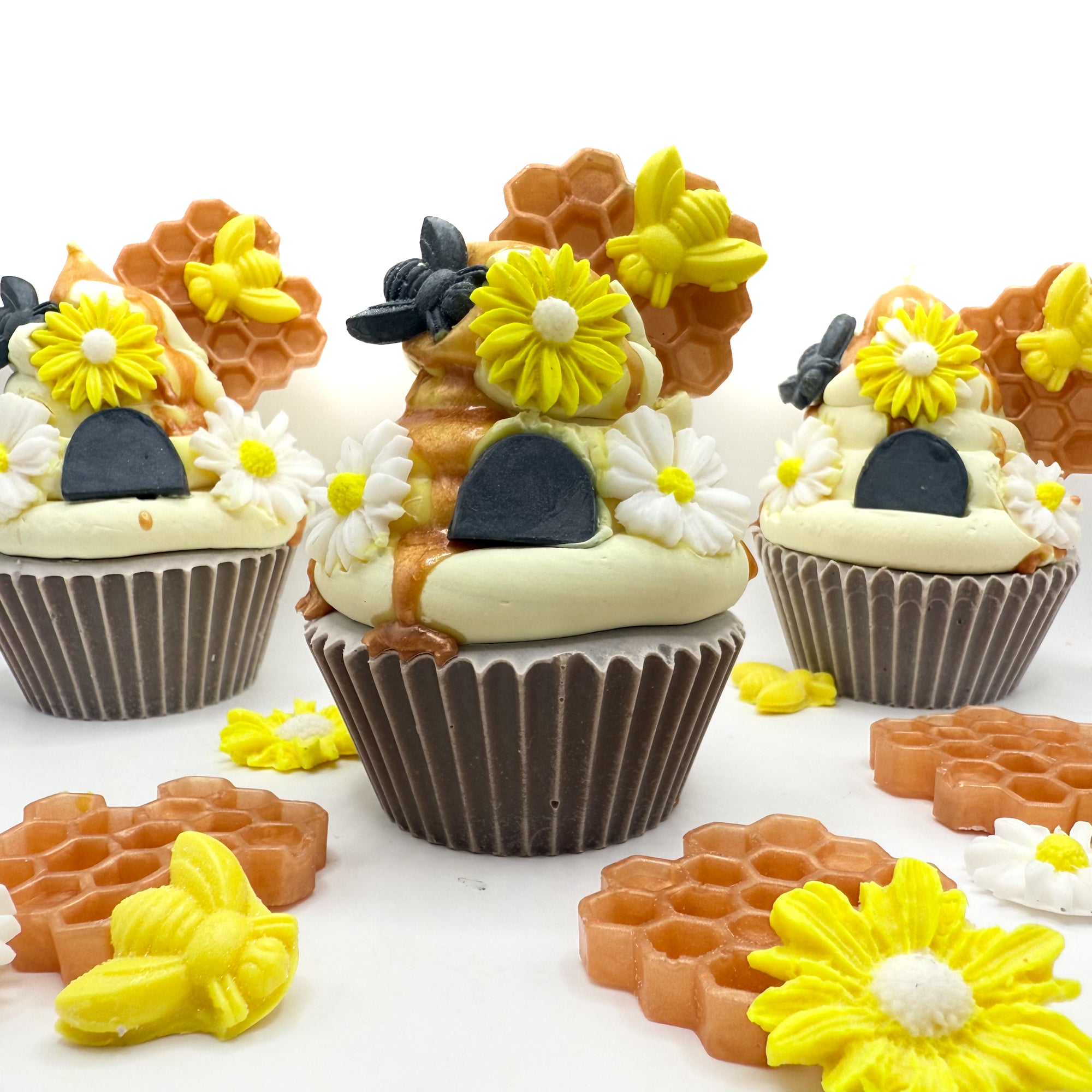 Group of Beehive cupcake soaps featuring piped frosting and soap embellishments like honeycomb, daisies, and bees.