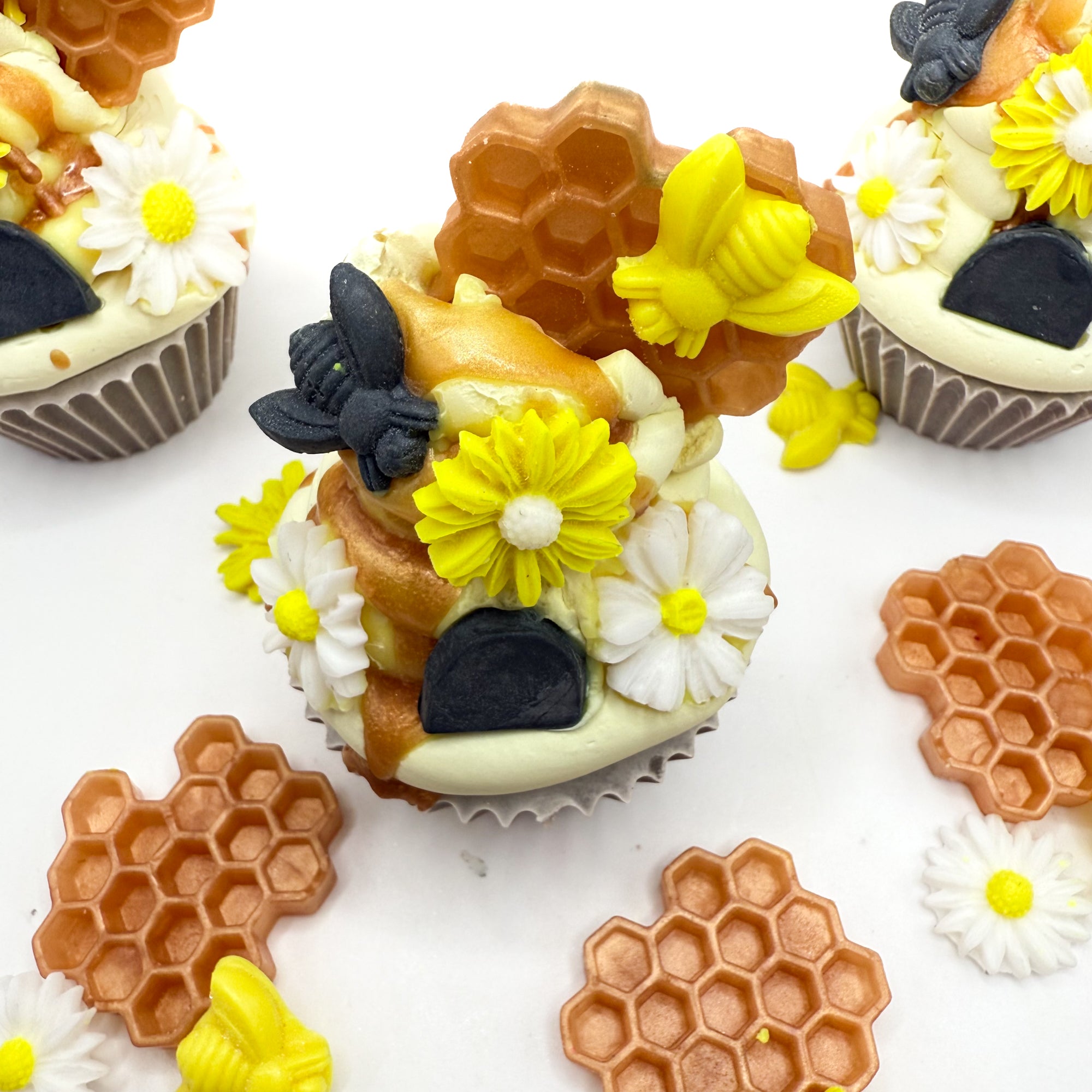 Top view of Beehive cupcake soaps highlighting hand-piped frosting and colorful soap embellishments of honeycomb, bees, and flowers.