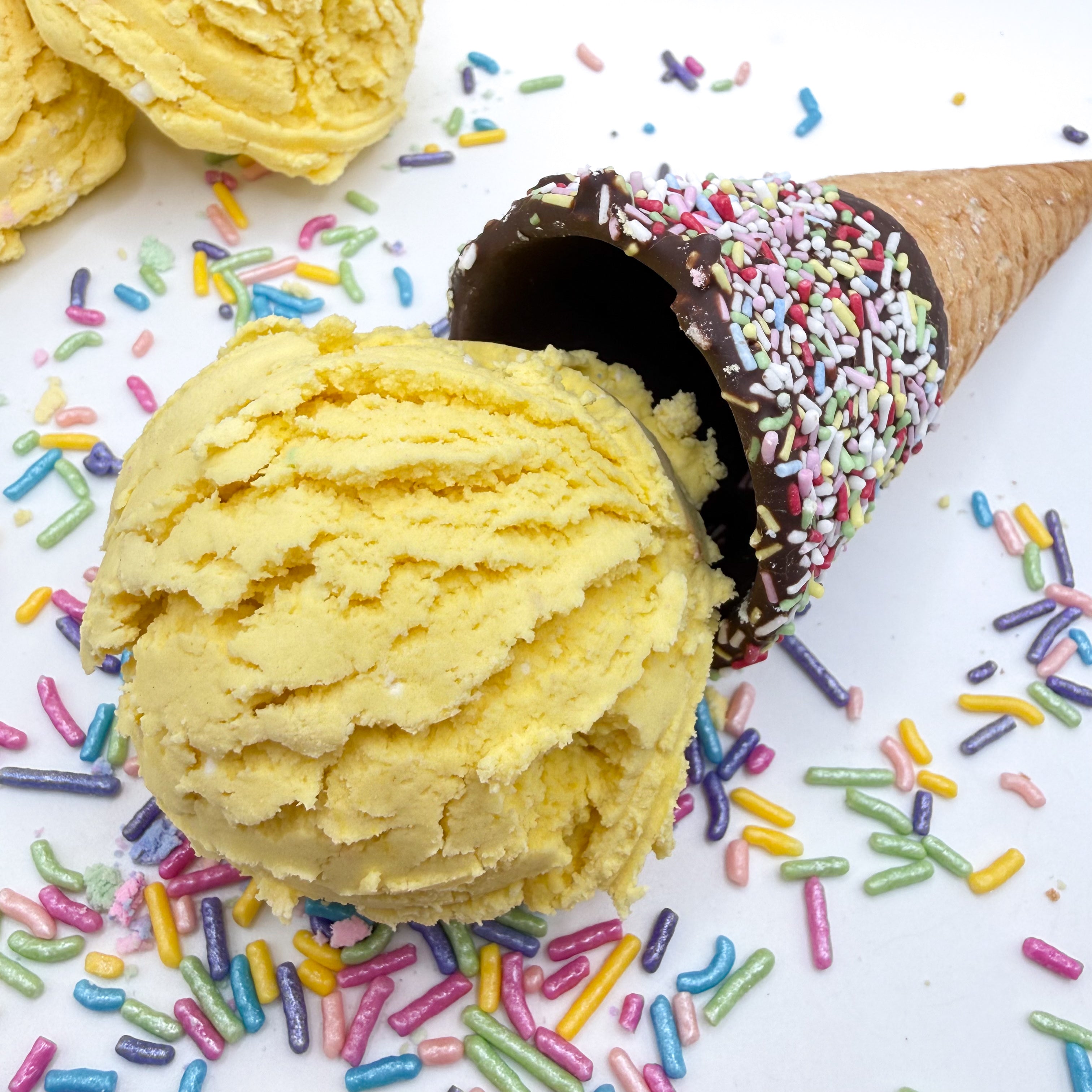 One yellow bubble bath scoops for a surprise choice handmade by Rusted Acre Soap Co. Scoop looks like a yellow ice cream scoop with sprinkles and ice cream cone prop on a white background.