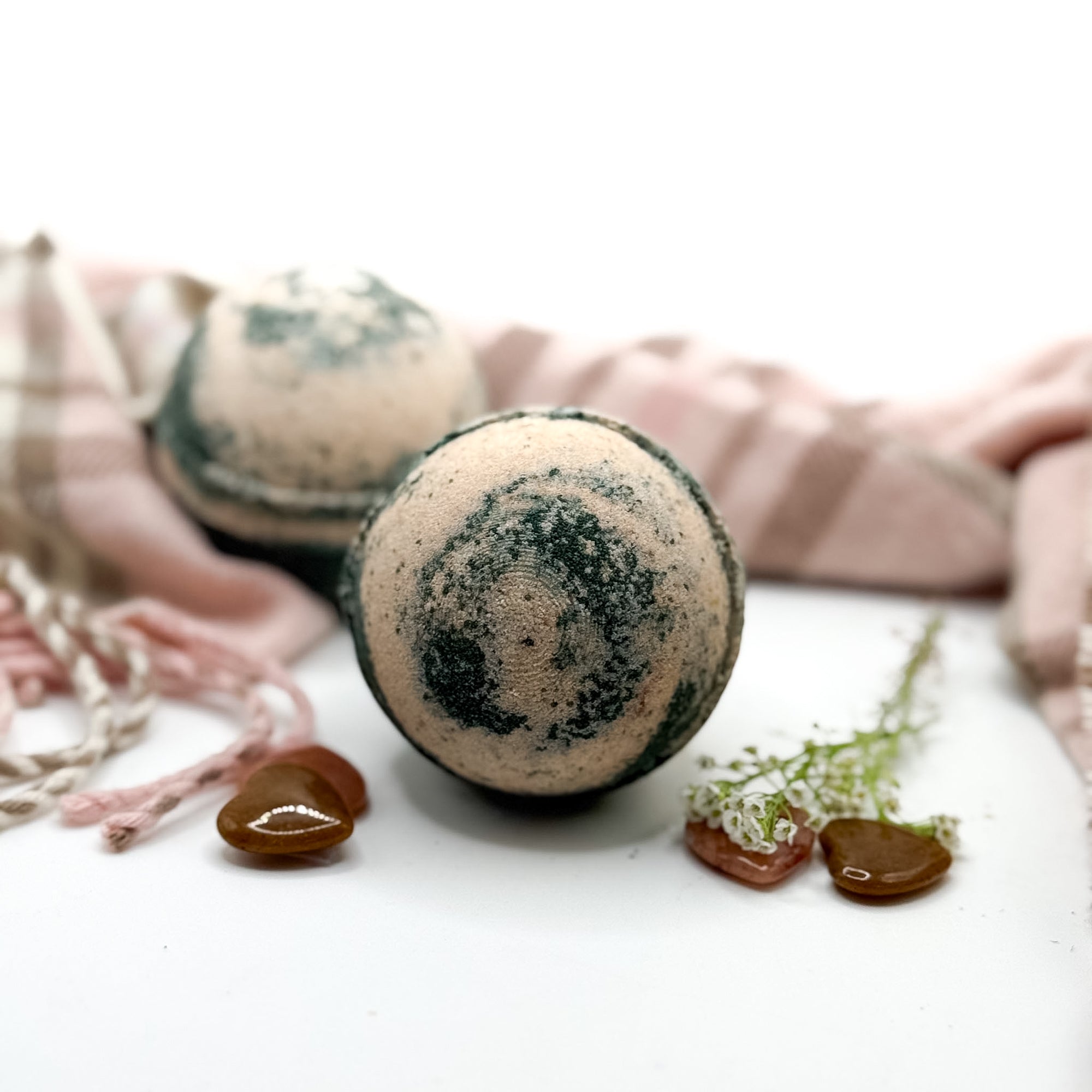 Two brown and tan cashmere bath bombs on a white background with props.