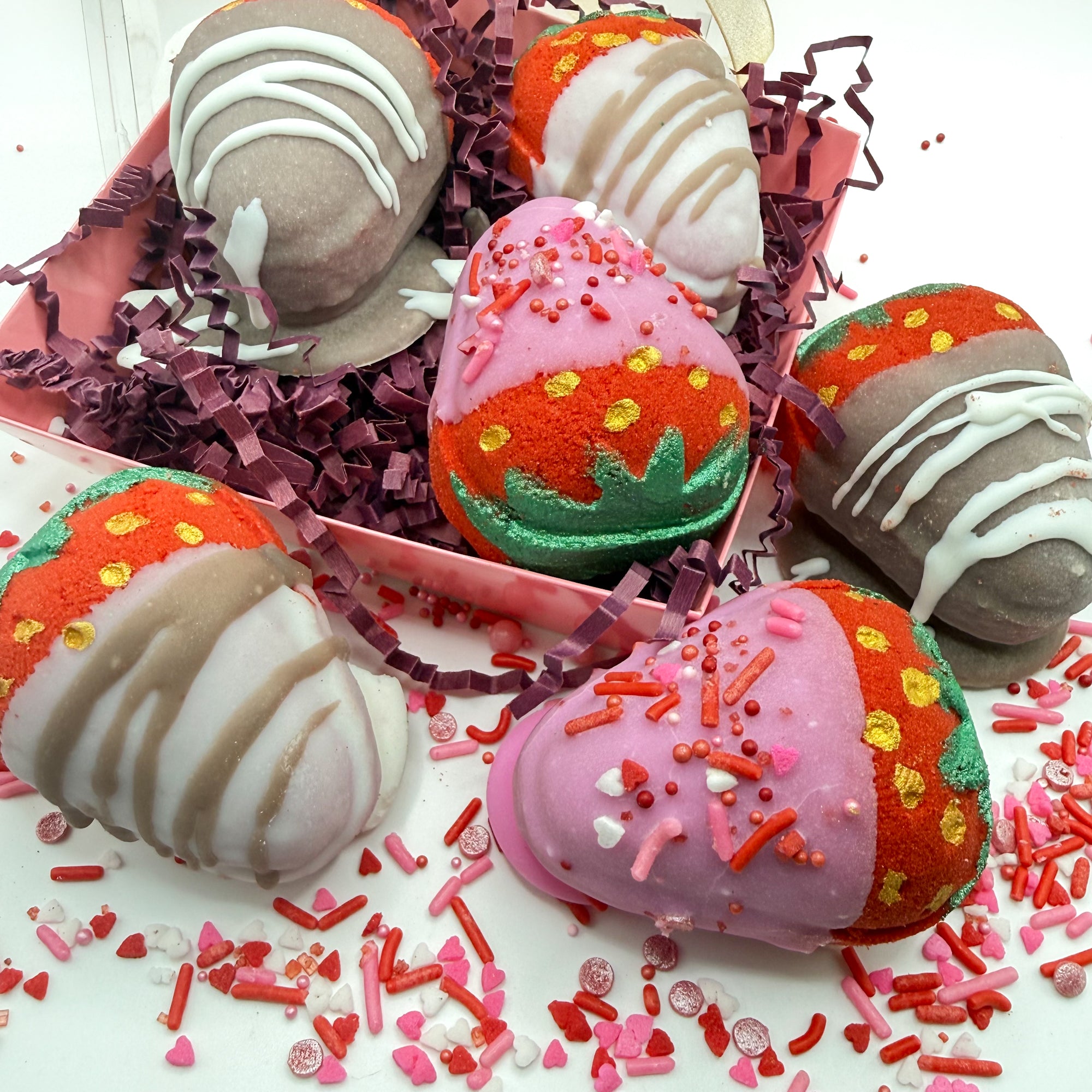 Multiple chocolate covered strawberry bath bombs hand made by Rusted Acre Soap Co with pink, white and brown chocolate hand dipped to look regular strawberries.
