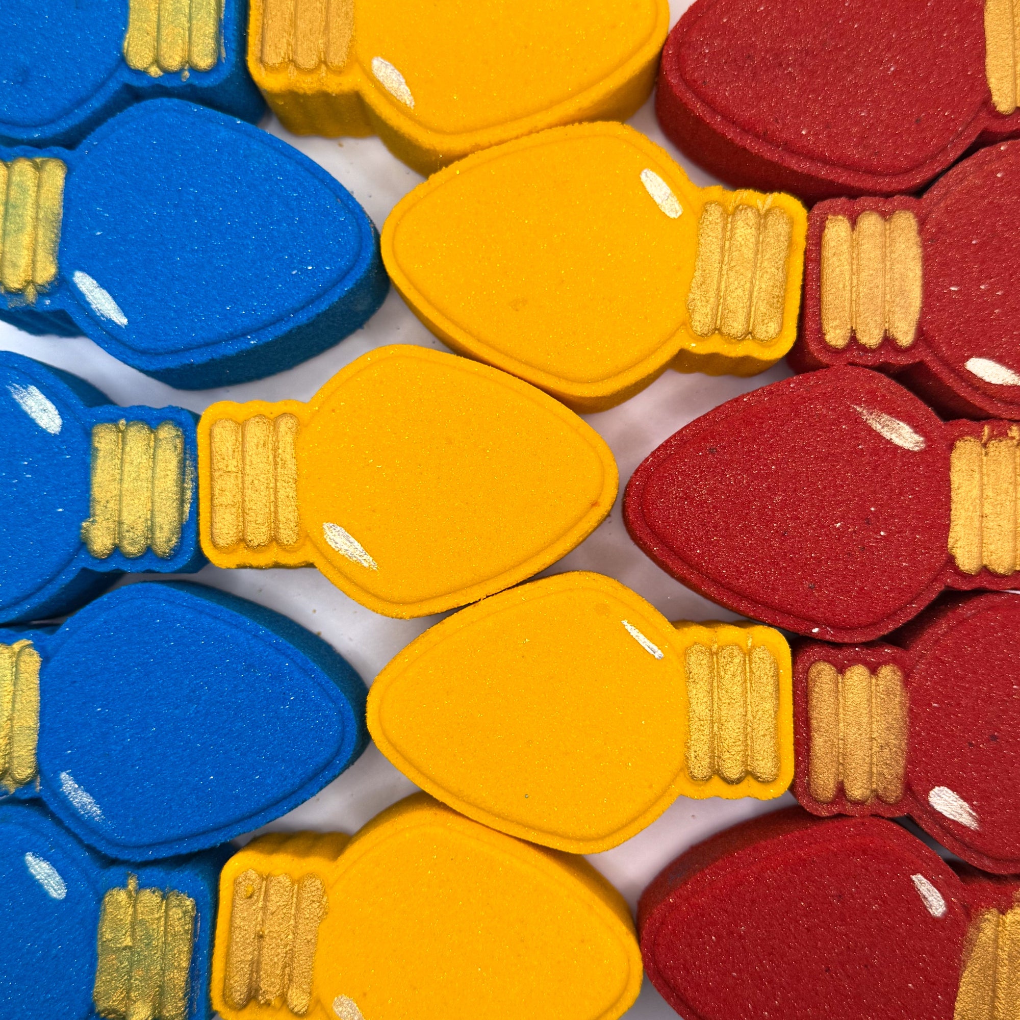 Colorful Christmas light bulb shaped bath bombs in red, yellow, and blue.