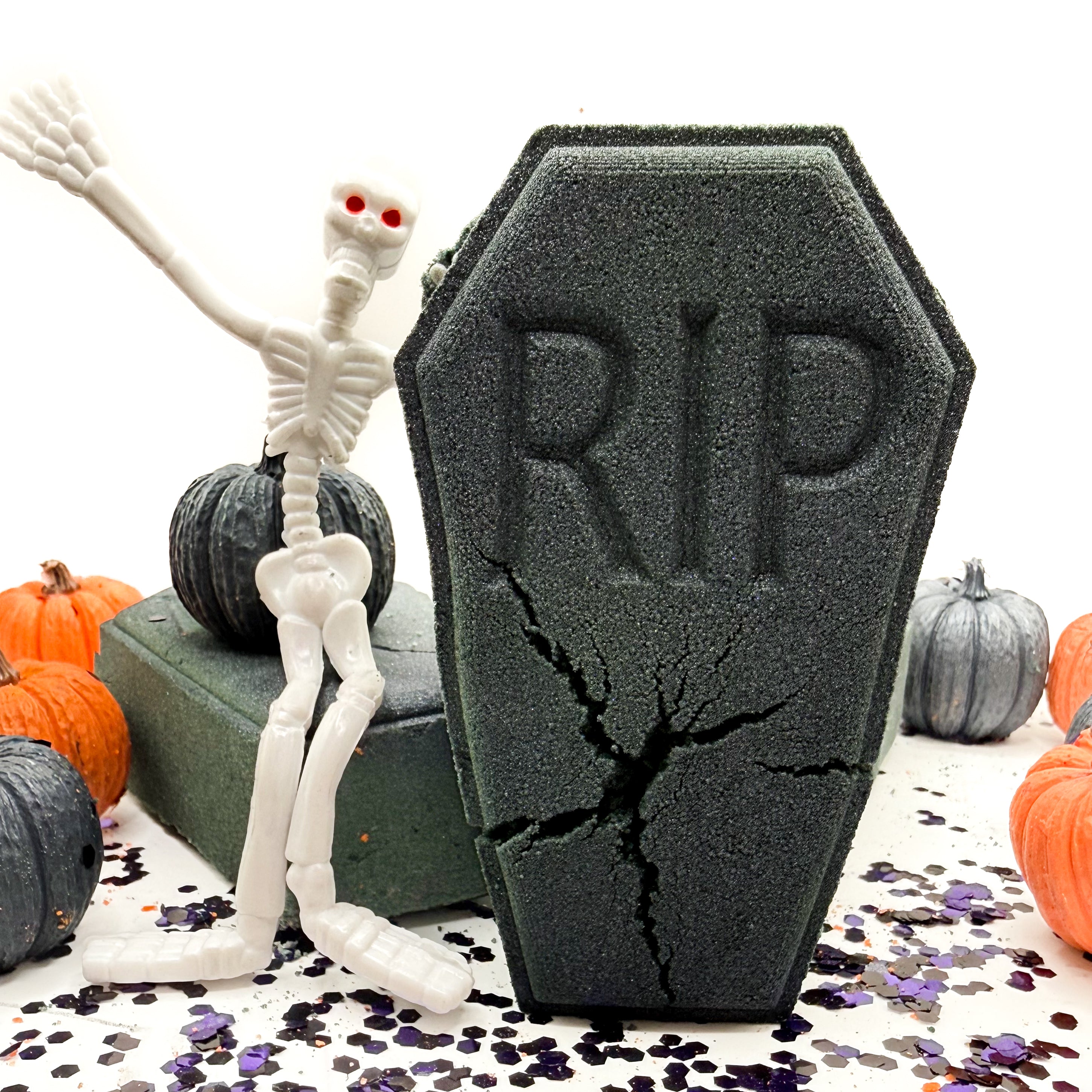 A dark blue-purple coffin with an orange hand sticking out. The letters RIP embossed on the front.