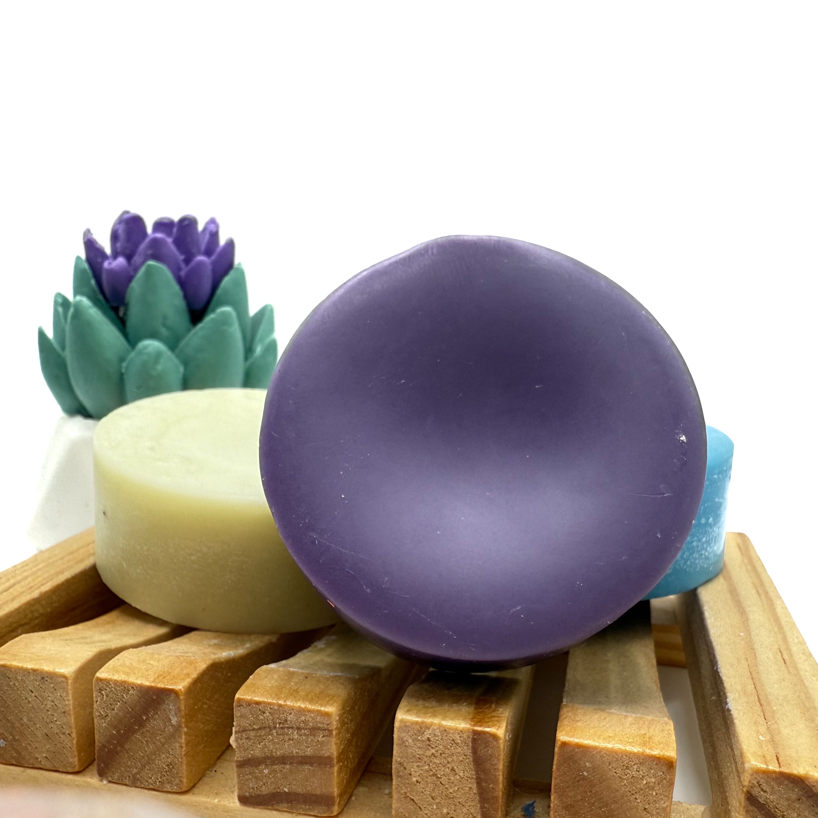 Round dark purple conditioner bar for hair on wood soap lift.