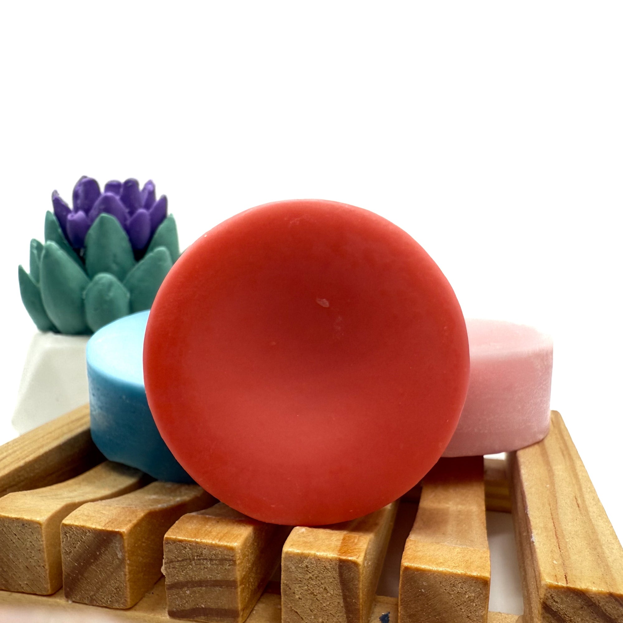 Round dark pink conditioner bar for hair on wood soap lift.