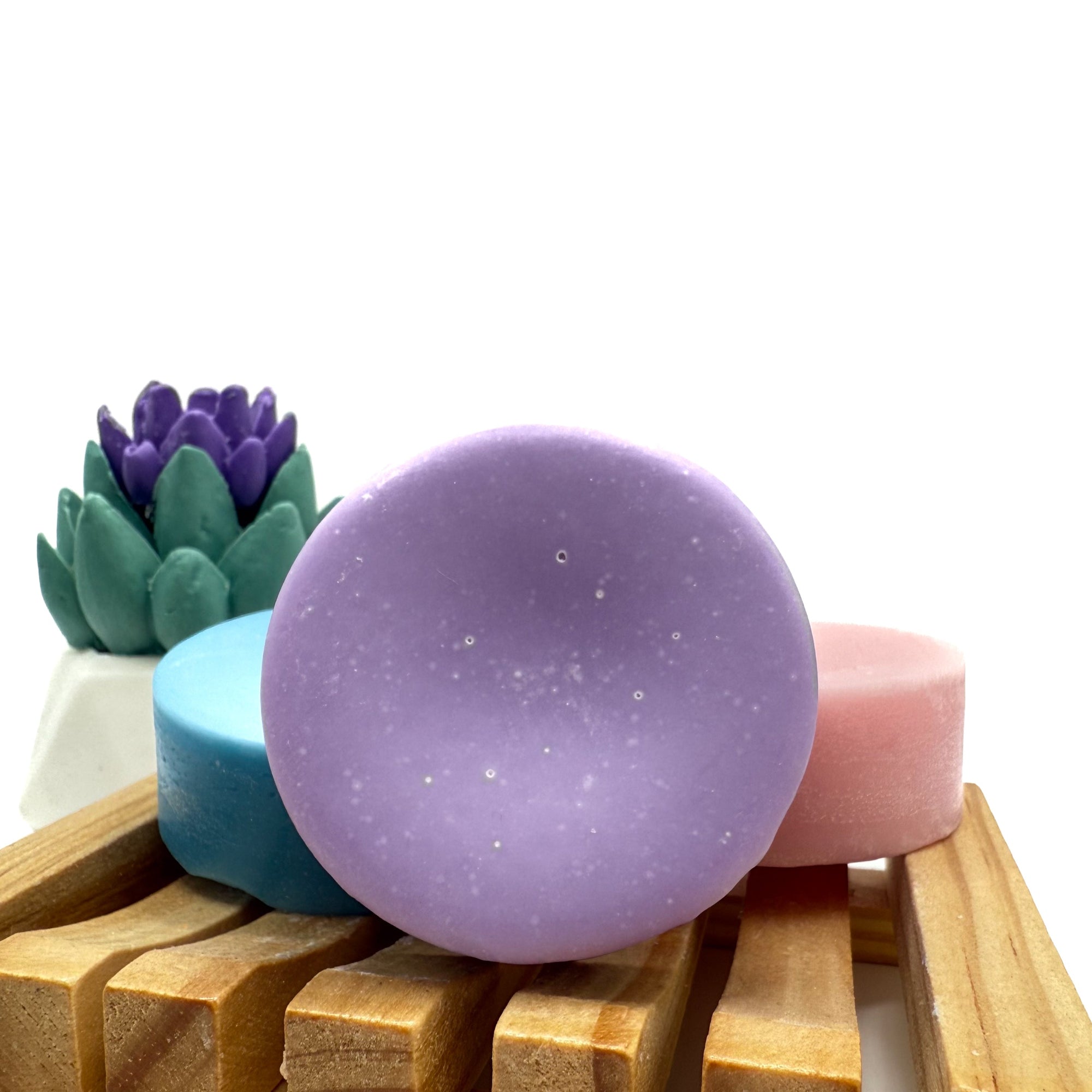 Round purple conditioner bar for hair on wood soap lift.