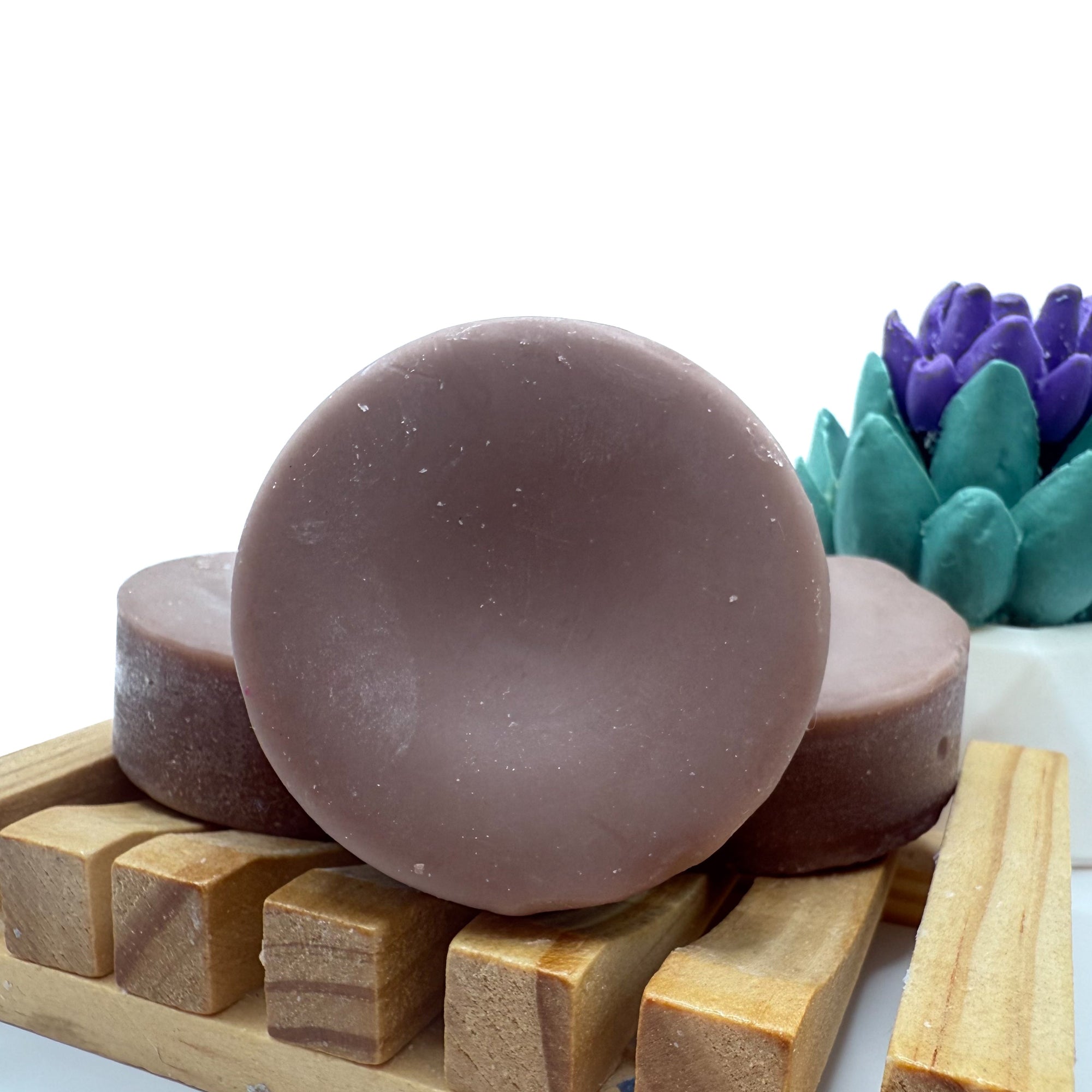 Round brown conditioner bar for hair on wood soap lift.