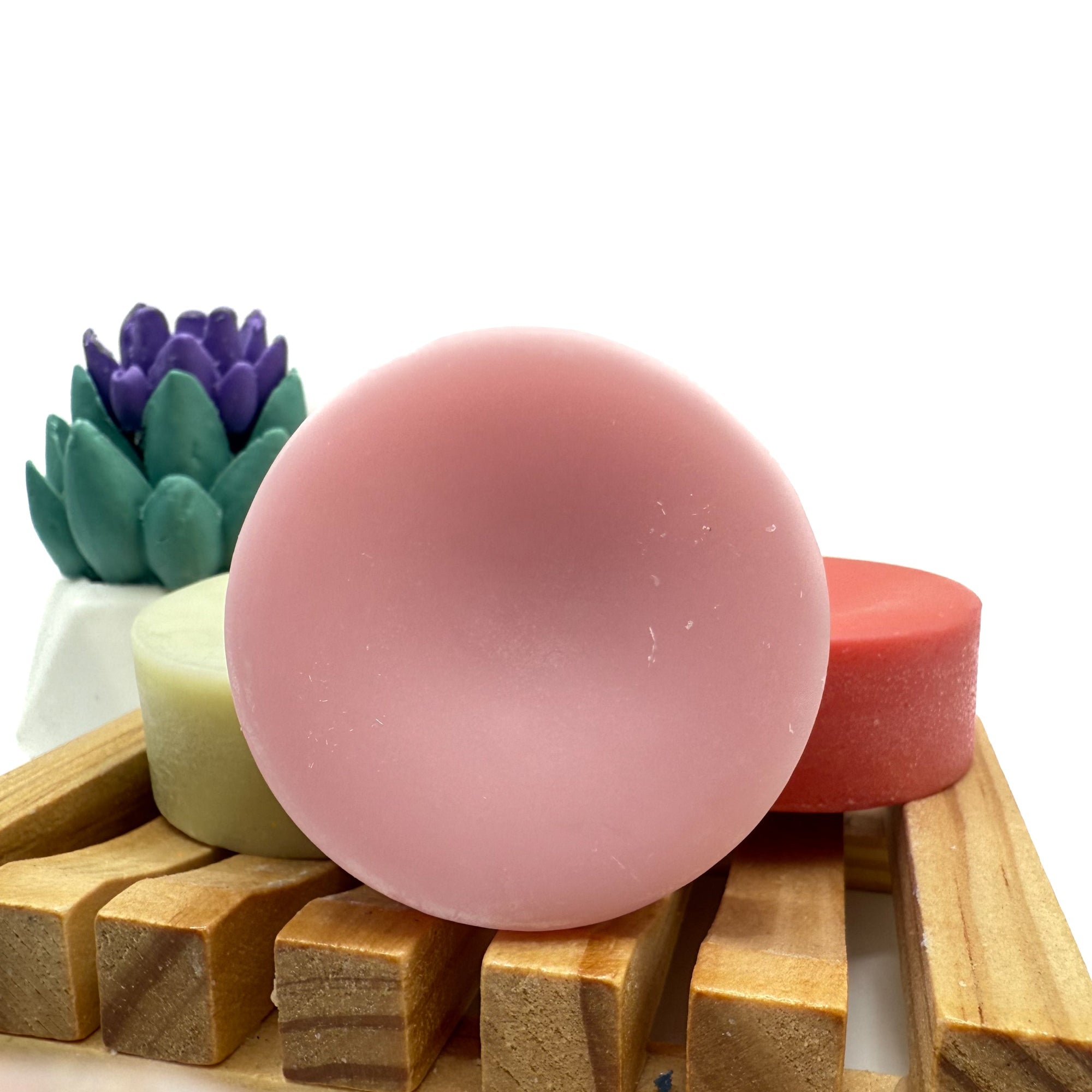 Round pink conditioner bar for hair on wood soap lift.