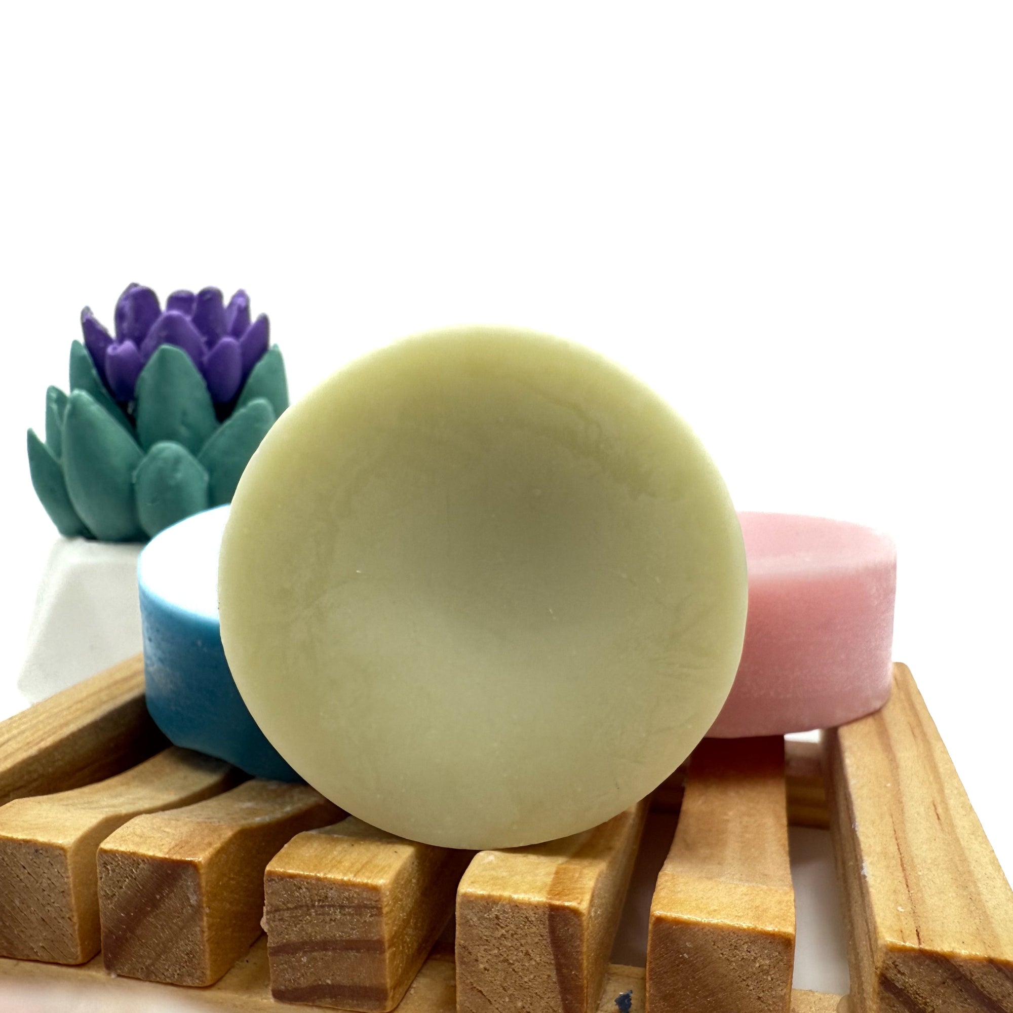 Round green conditioner bar for hair on wood soap lift.