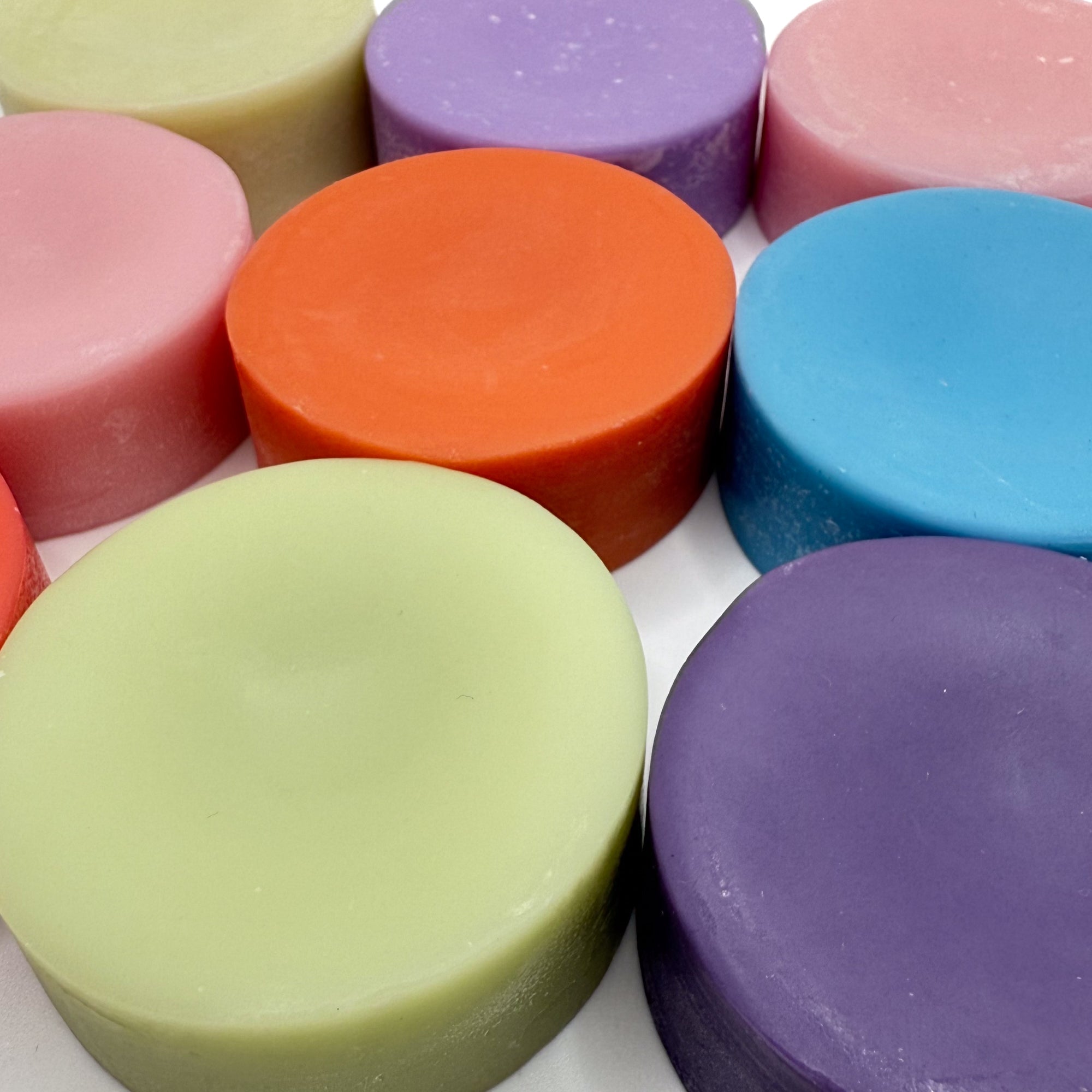 Multi colored conditioner bars laying flat displayed in rows varying colors.