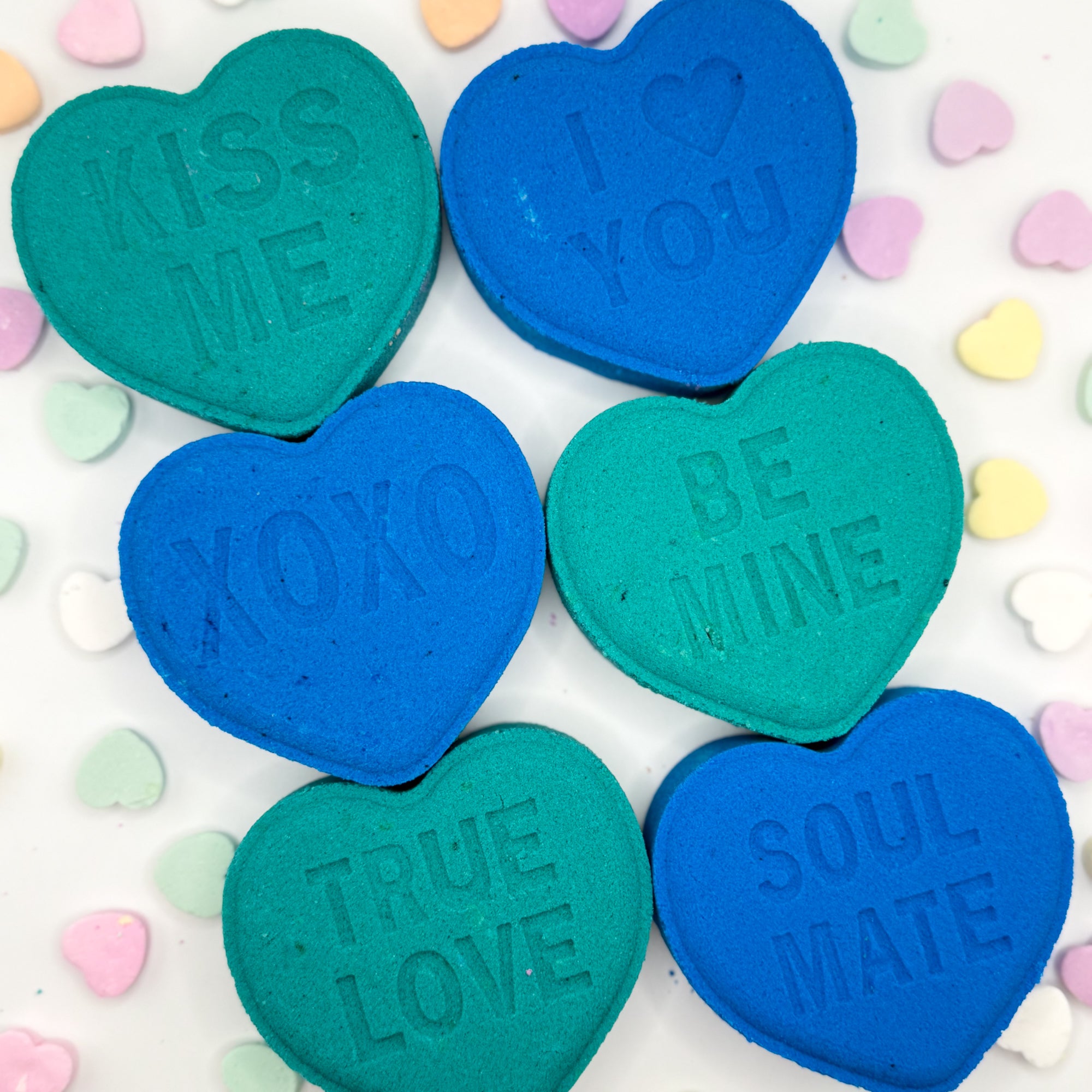 Heart shaped bath bombs blue and green with valentines sayings on a colorful background