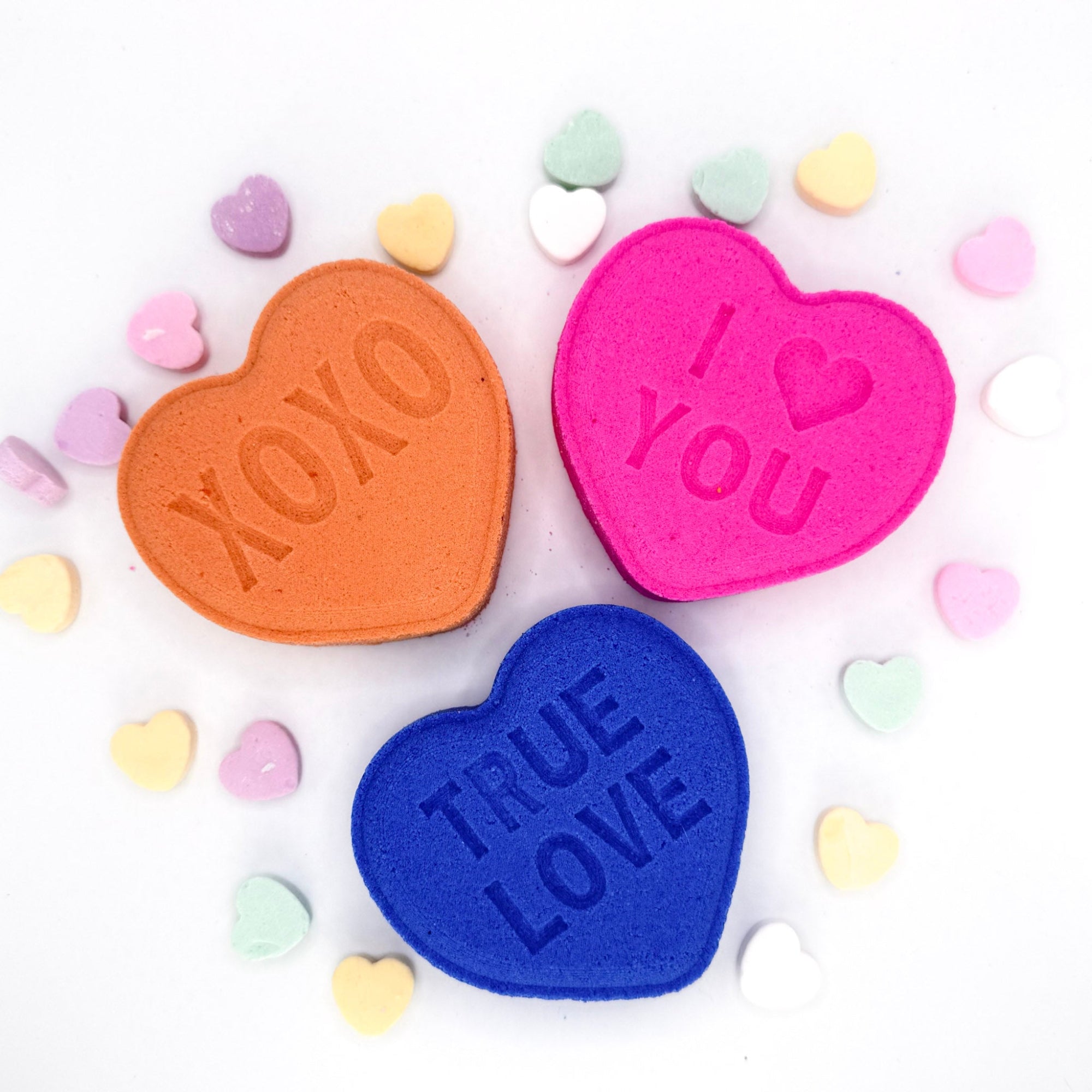 Heart bath bombs with messages from Rusted Acre Soap Company. Three hearts in pink, purple and peach.