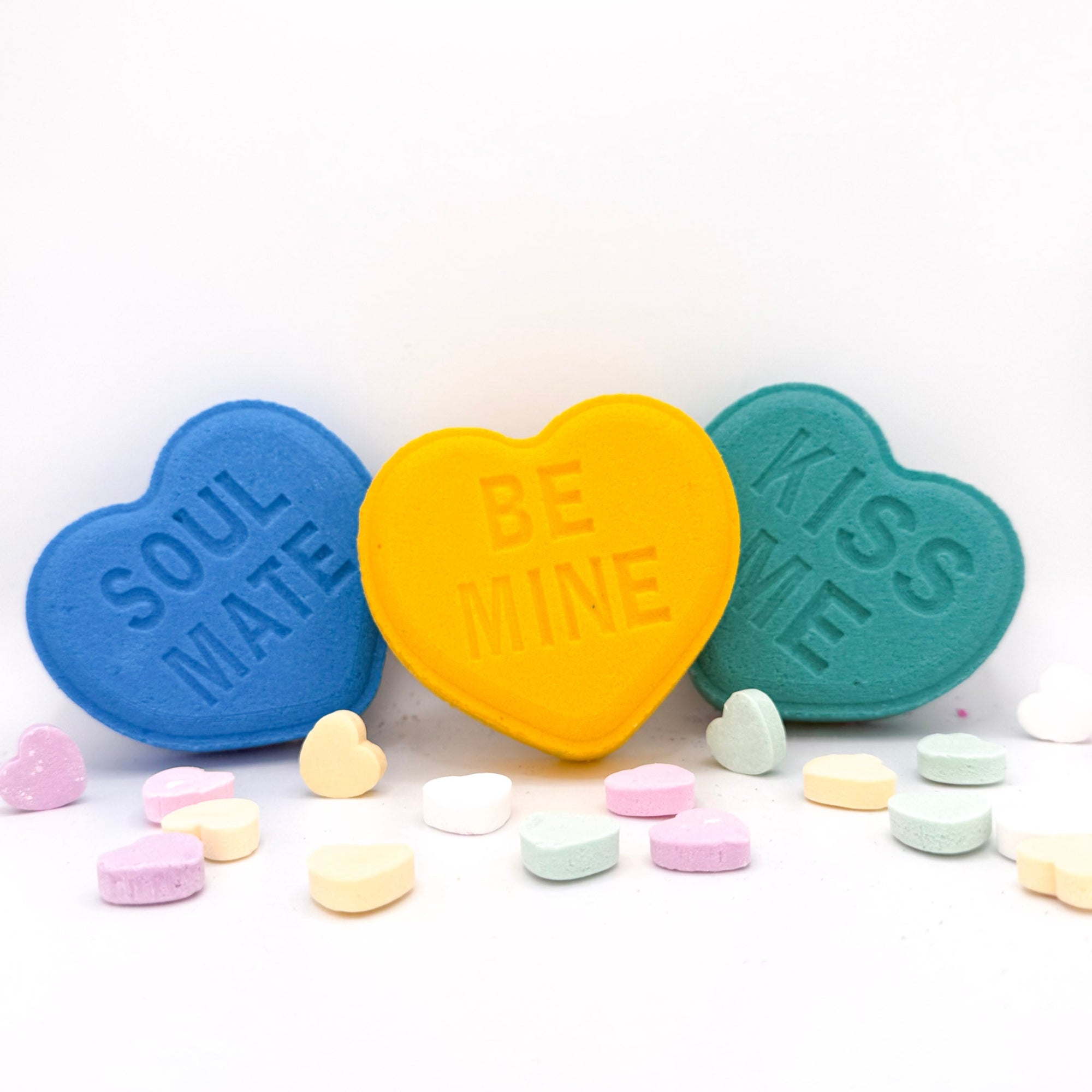 Heart bath bombs front view with messages from Rusted Acre Soap Company. Three hearts in blue, yellow and green.