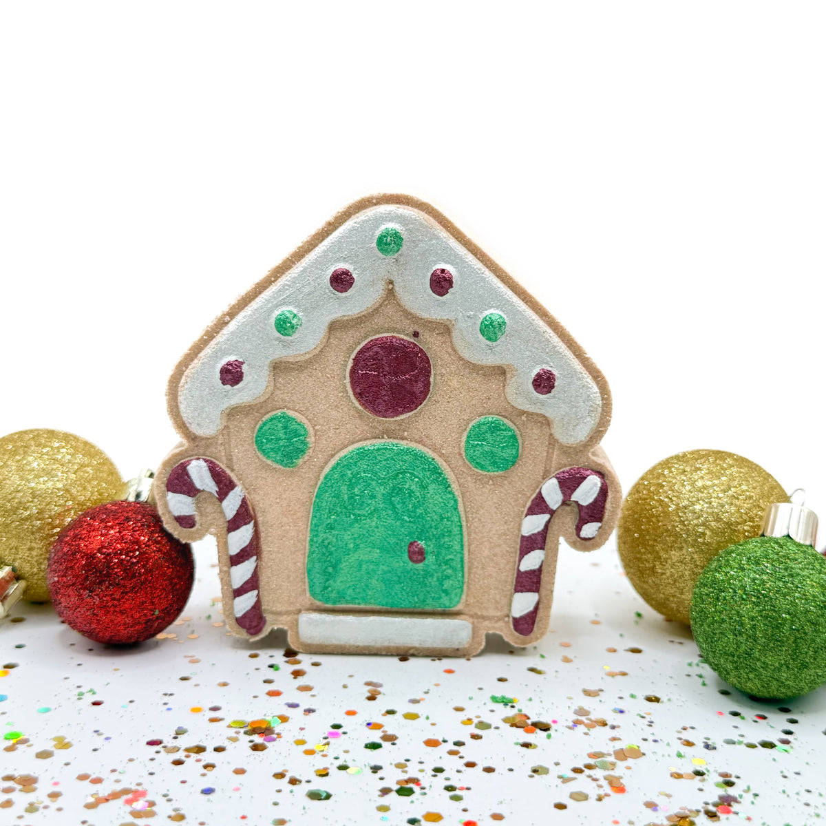 One gingerbread house shape and scent bath bomb. Hand-painted white overhang, and door, colorful lights, candy canes on each side of door.