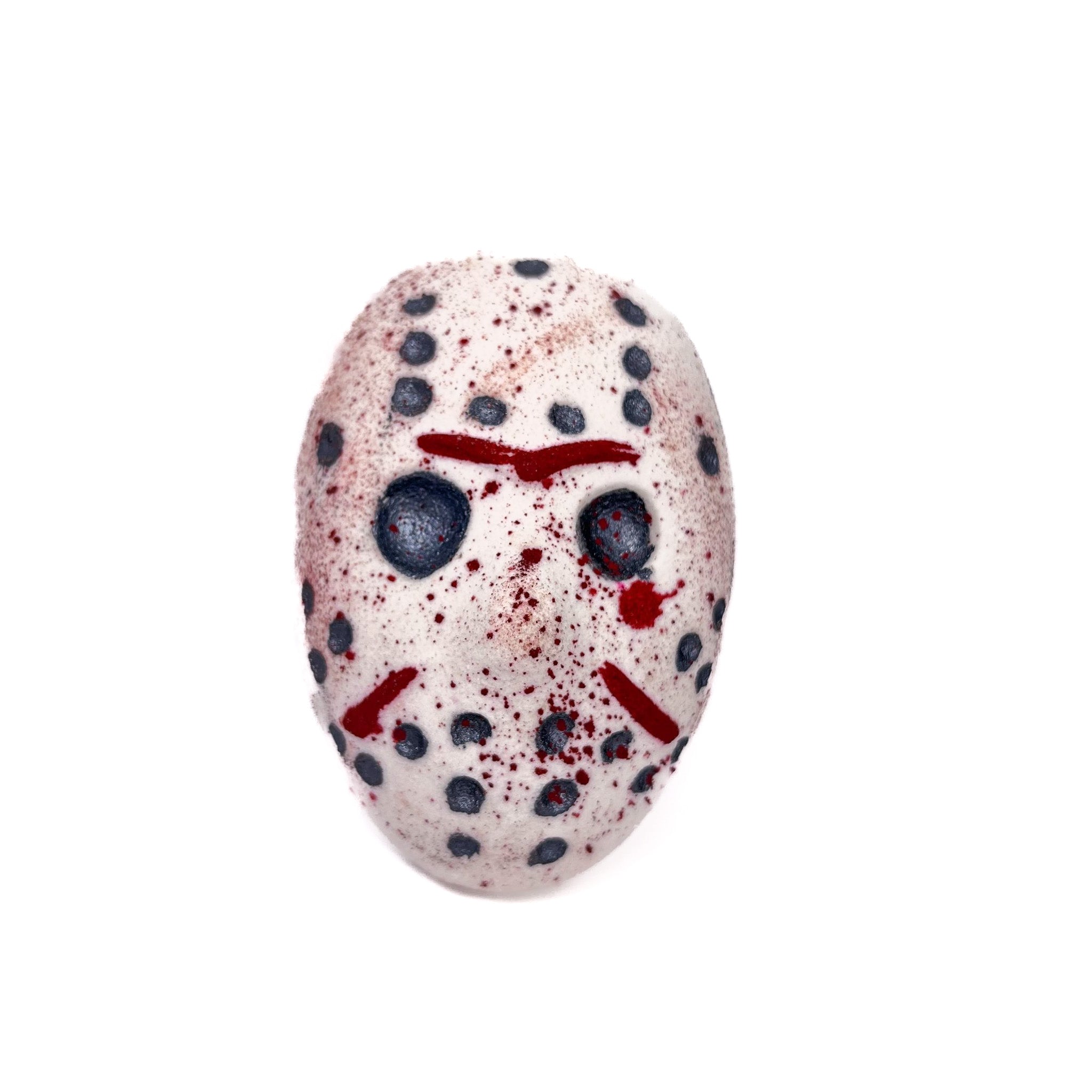 A hockey mask shaped bath bomb hand-painted black dots and eyes. Made to look a little dingy and splattered with red mica like blood!