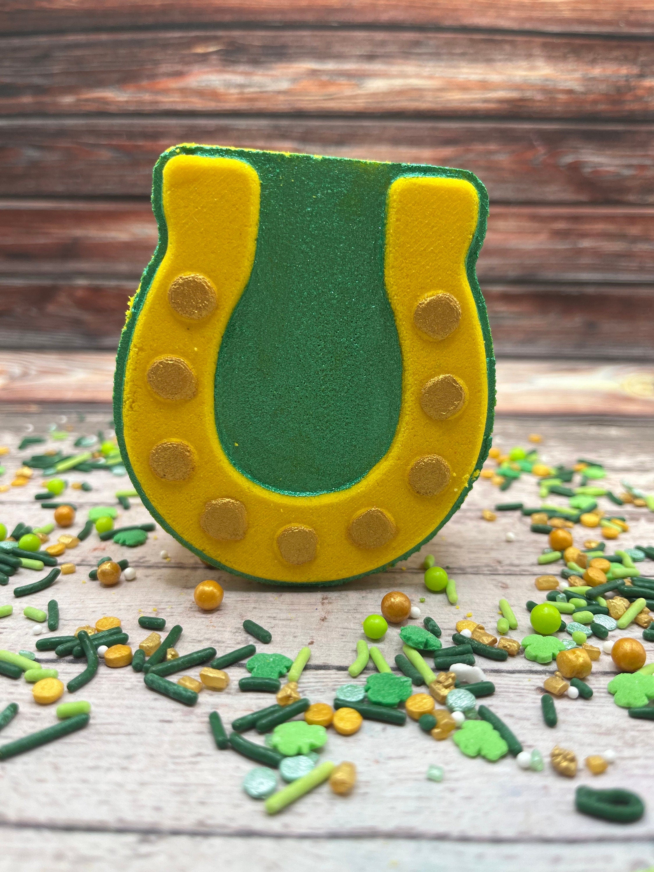 Horseshoe shaped bath bomb. Color is yellow with hand-painted green background