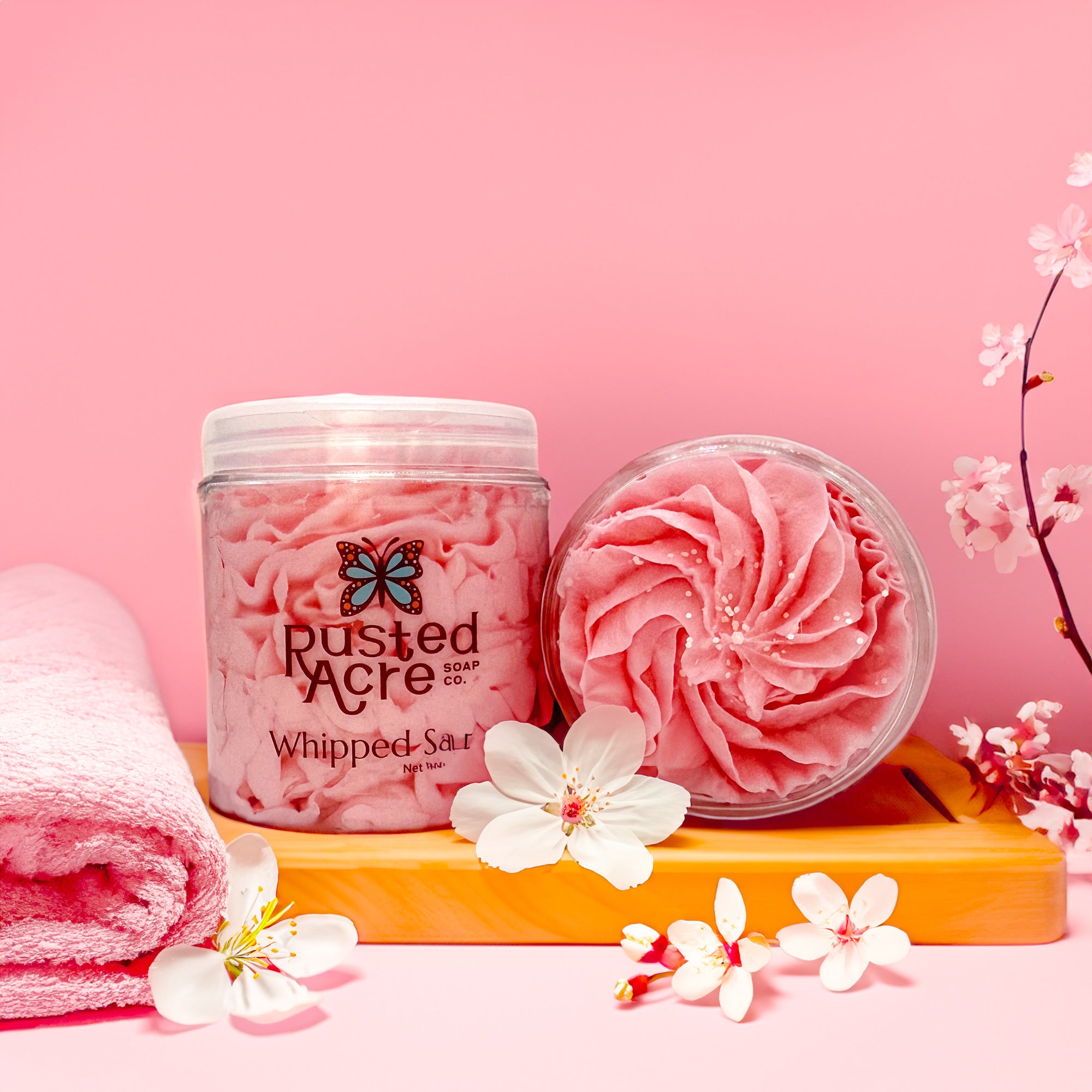 Two jars of Rusted Acre Soap Company’s Japanese Cherry Blossom whipped soap front and top view in a lifestyle setting.