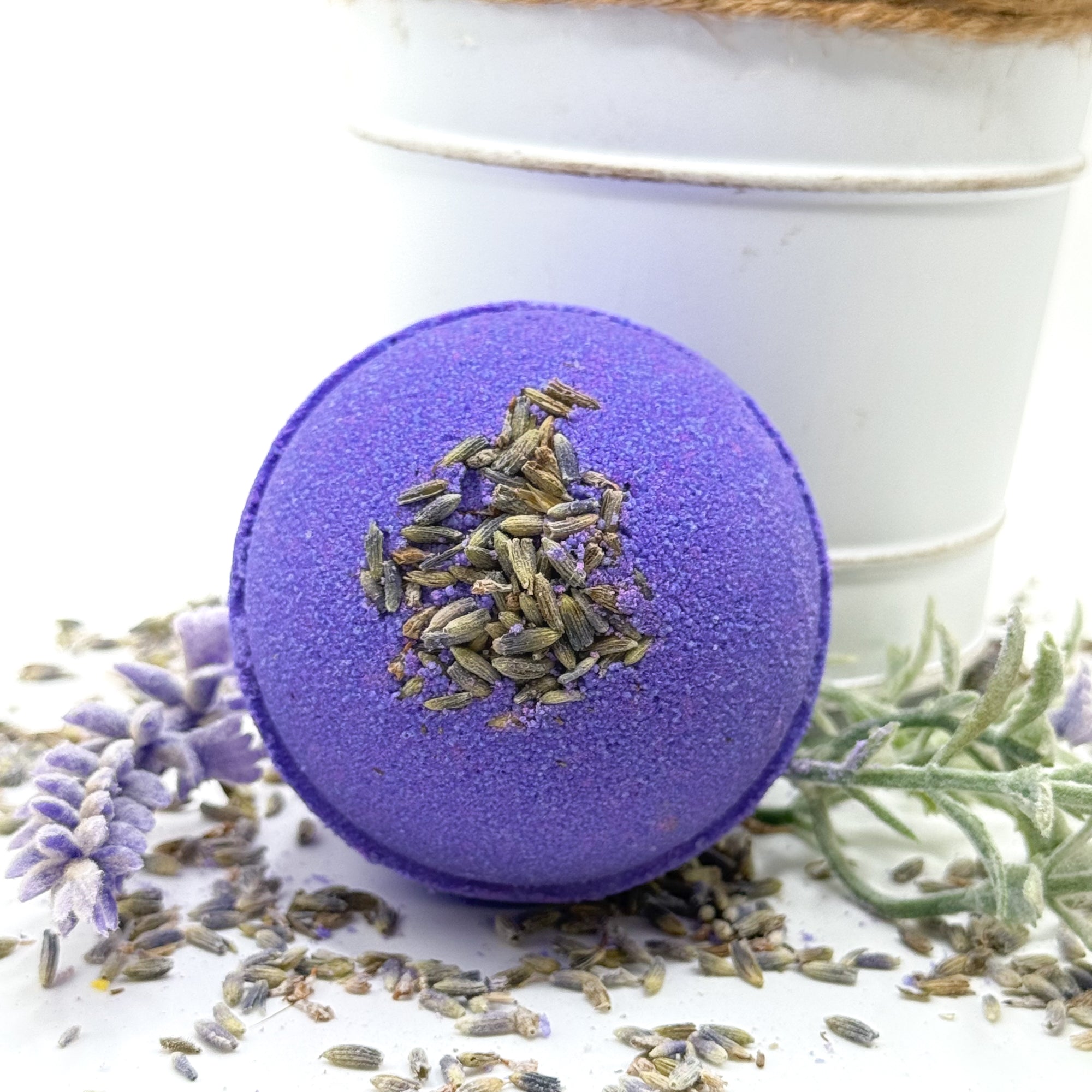 One purple round, lavender scent bath bomb. Displayed with lavender buds.