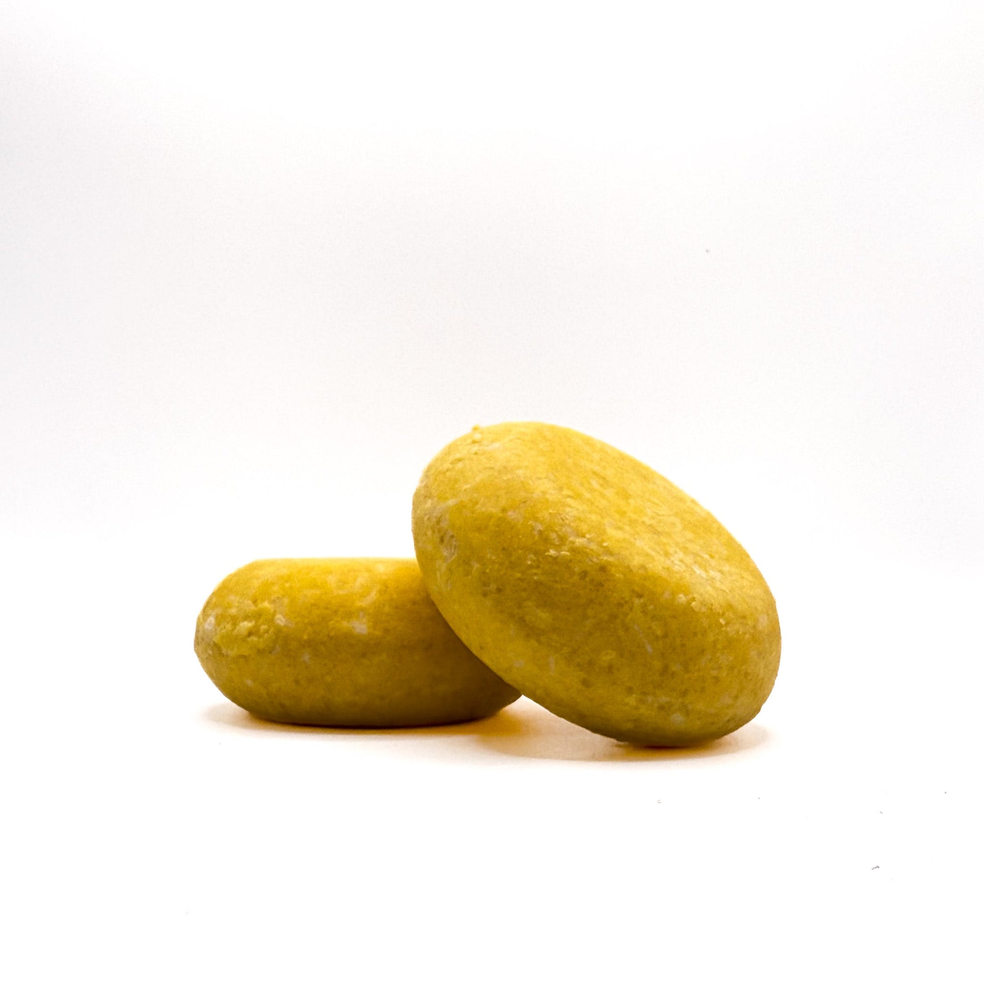 Two yellow zero waste shampoo bars in lemon scent from Rusted Acre Soap Company.