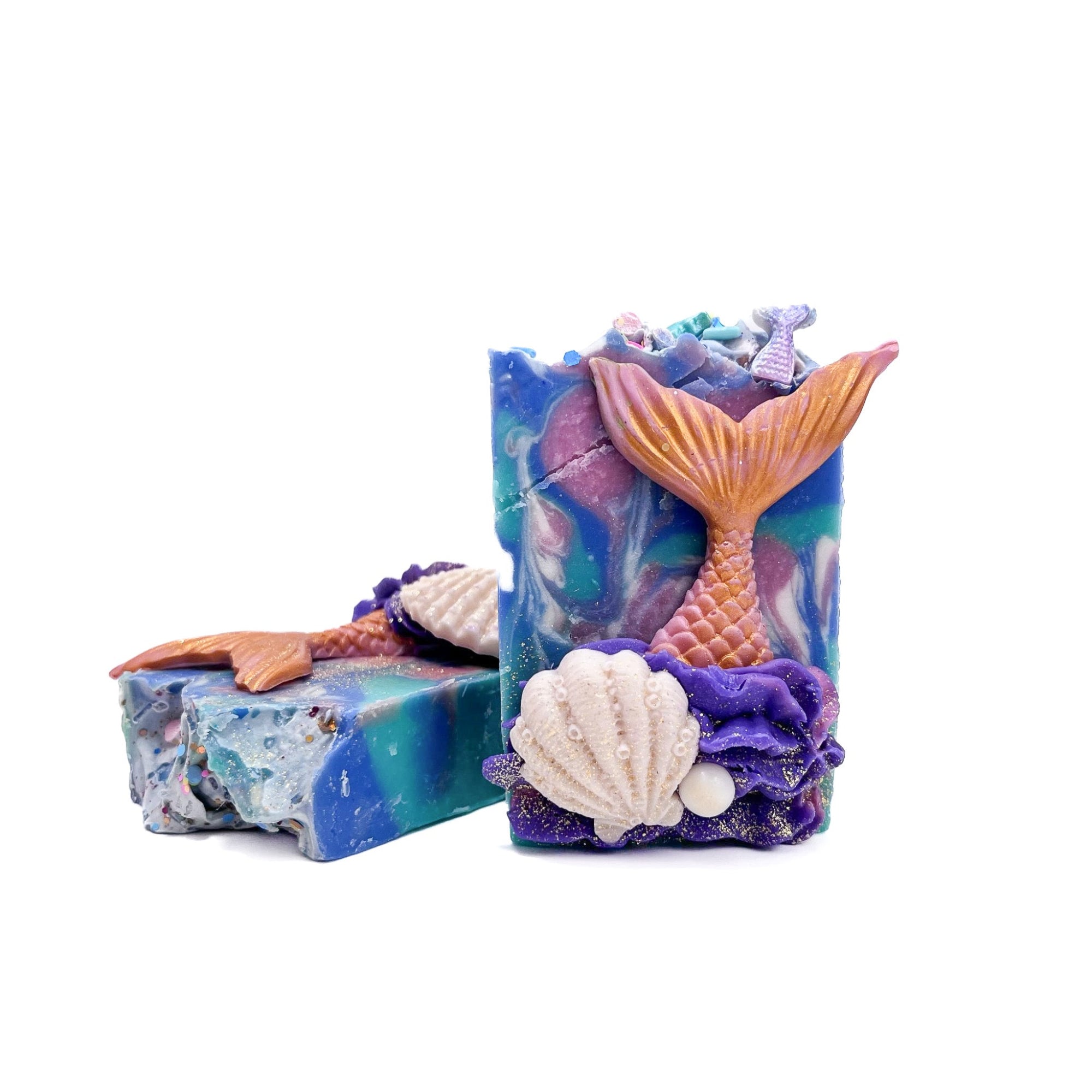 Two bars of Mermaid Tail handmade soap from Rusted Acre Soap Co.. A clam shell, a pearl, and a mermaid tail soap embed on the front.