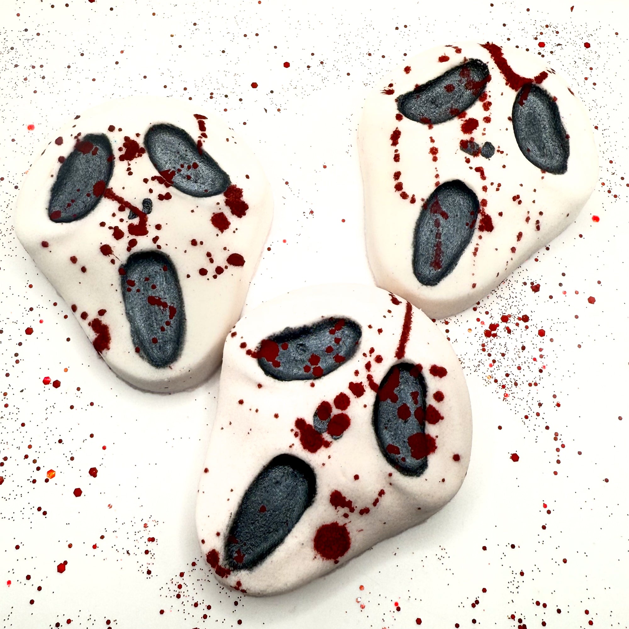 Set of three Midnight Caller horror-themed bath bombs, each with black facial features and red splatter accents.Handmade by Rusted Acre Soap Company.