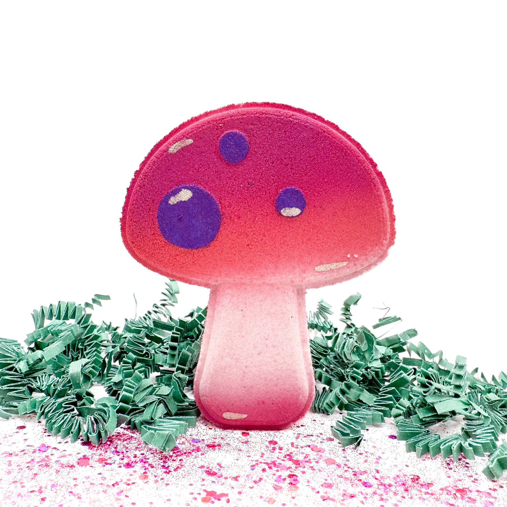 Pink mushroom-shaped bath bomb with purple spots on a white background
