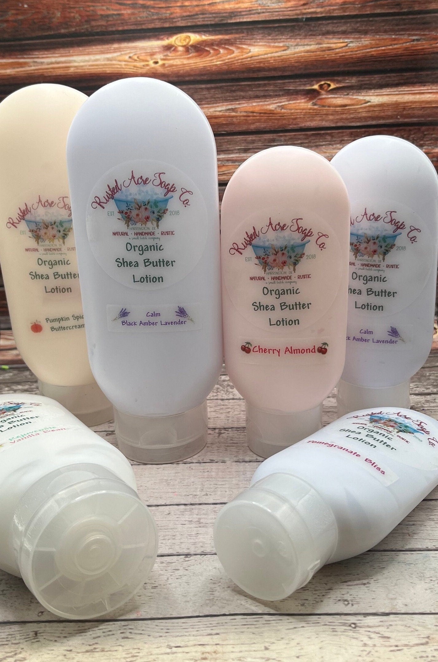 Six bottles of lotion, three, eight ounce, and three, four ounce sizes. Four standing two lying. Colors are pastel blues and peaches.