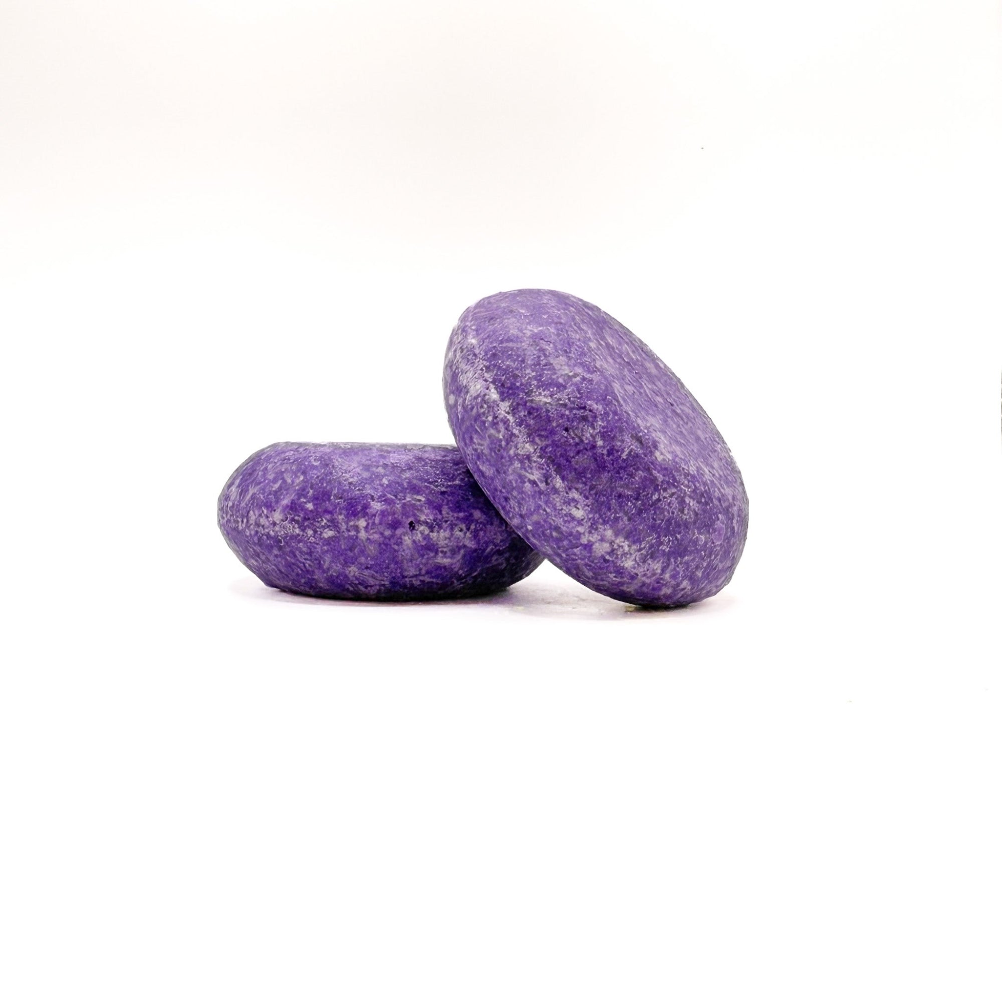 Two purple zero waste shampoo bars in pomegranate scent from Rusted Acre Soap Company.