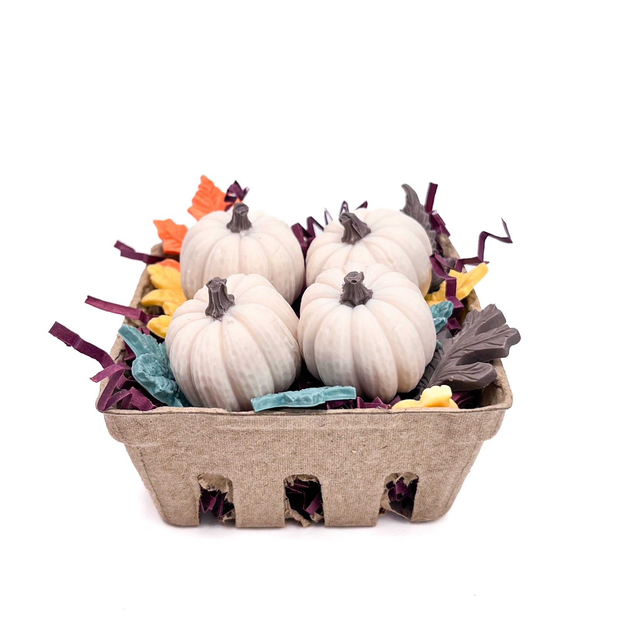 Four small white pumpkin soaps in a cardboard container with decorative ribbons on a white background.