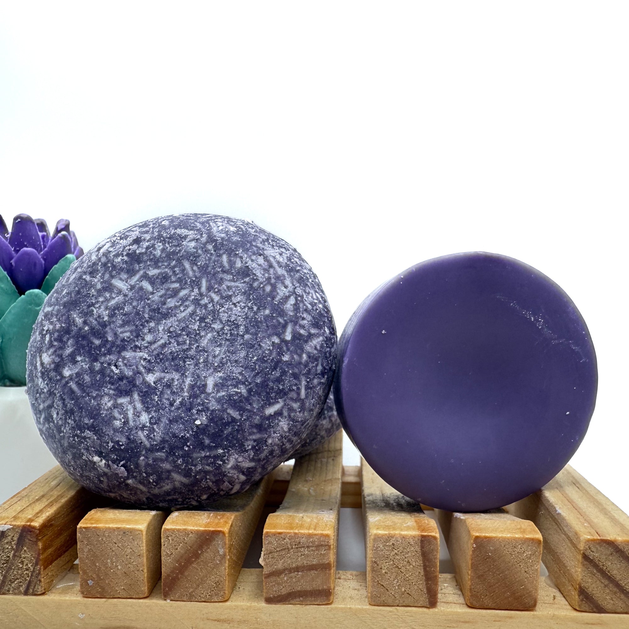 Enchanted zero waste Shampoo and Conditioner bar on a wood soap dish with a white background standing on side.