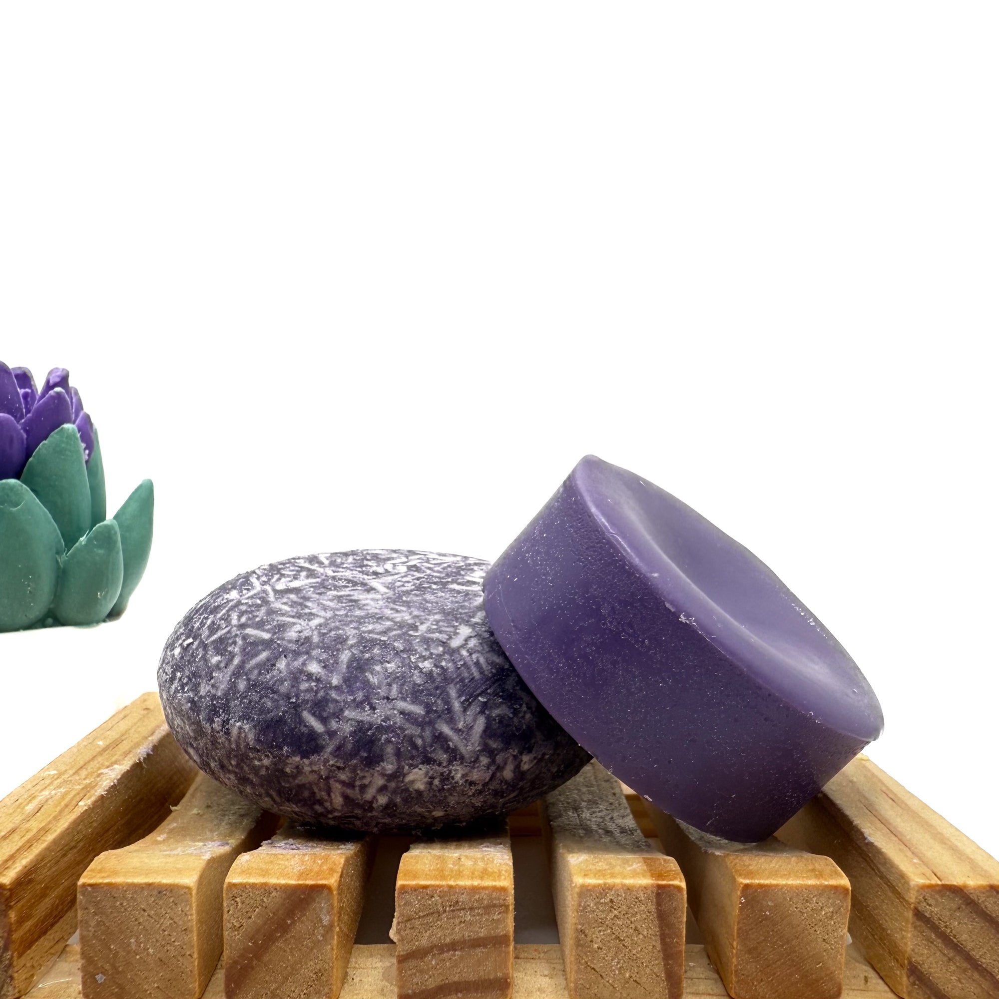 Dark purple enchanted zero waste Shampoo and Conditioner bar on a wood soap dish with a white background.