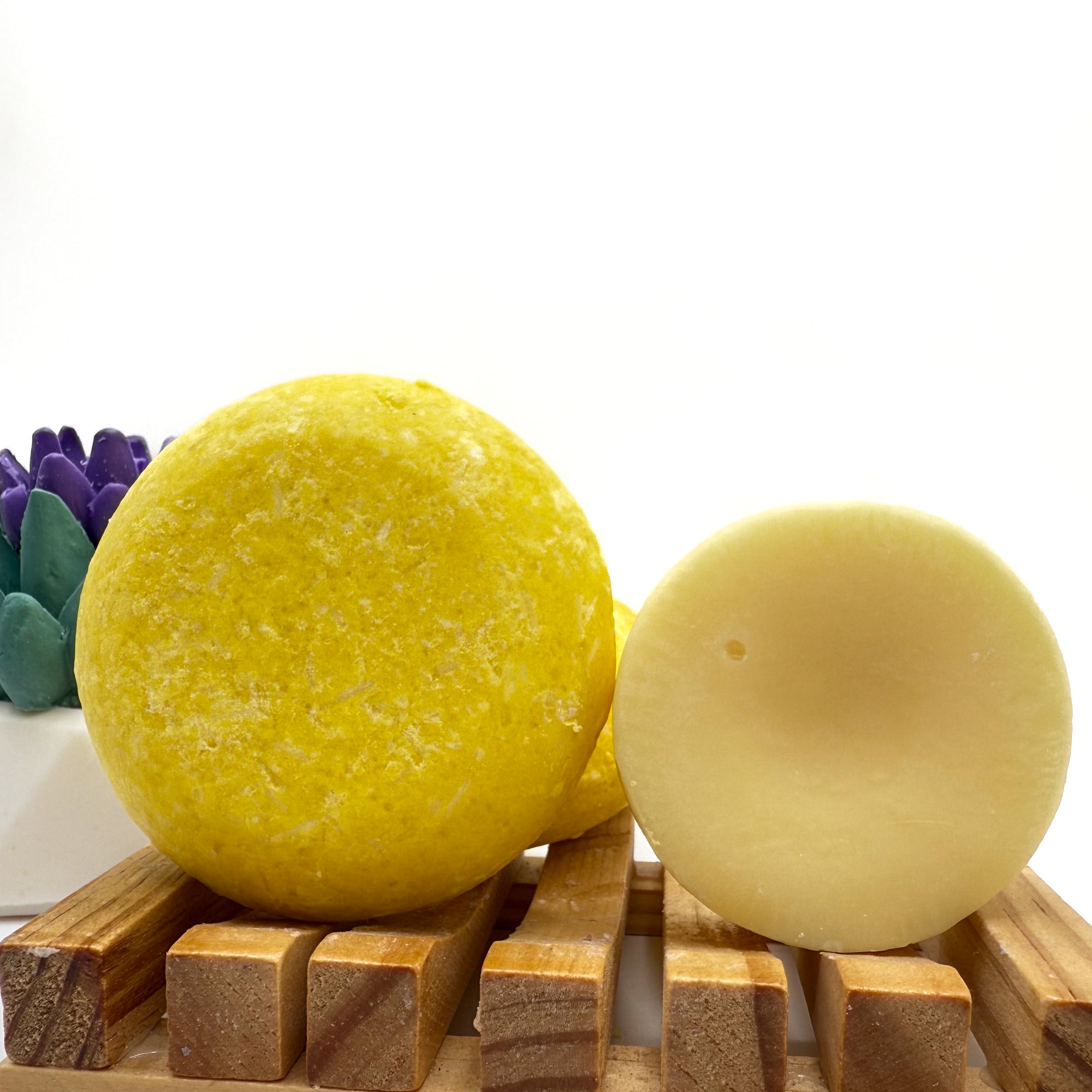 Yellow lemon love zero waste Shampoo and Conditioner bar on a wood soap dish with a white background standing on side.