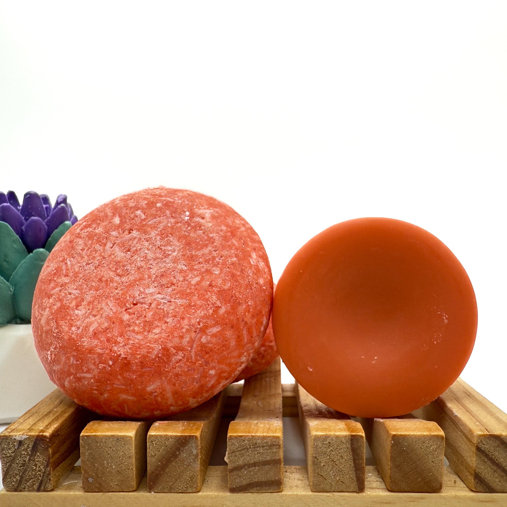 Orange mango tango zero waste Shampoo and Conditioner bar on a wood soap dish with a white background standing on side.
