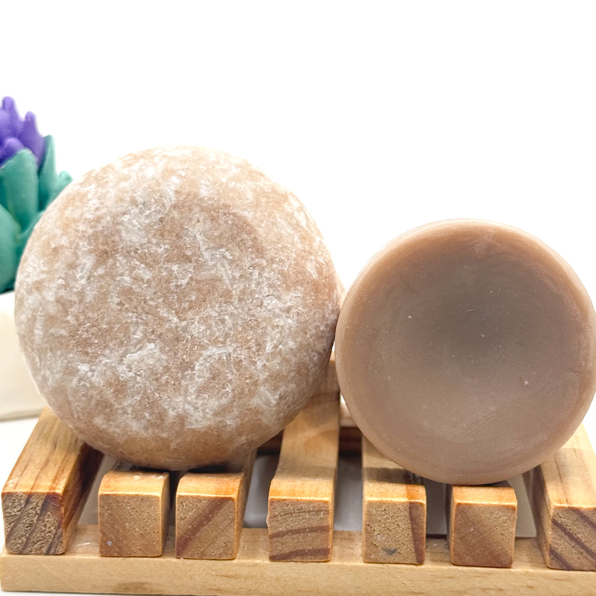 Zero waster rice protein shampoo and conditioner bars on a wooden stand with a blurred background.