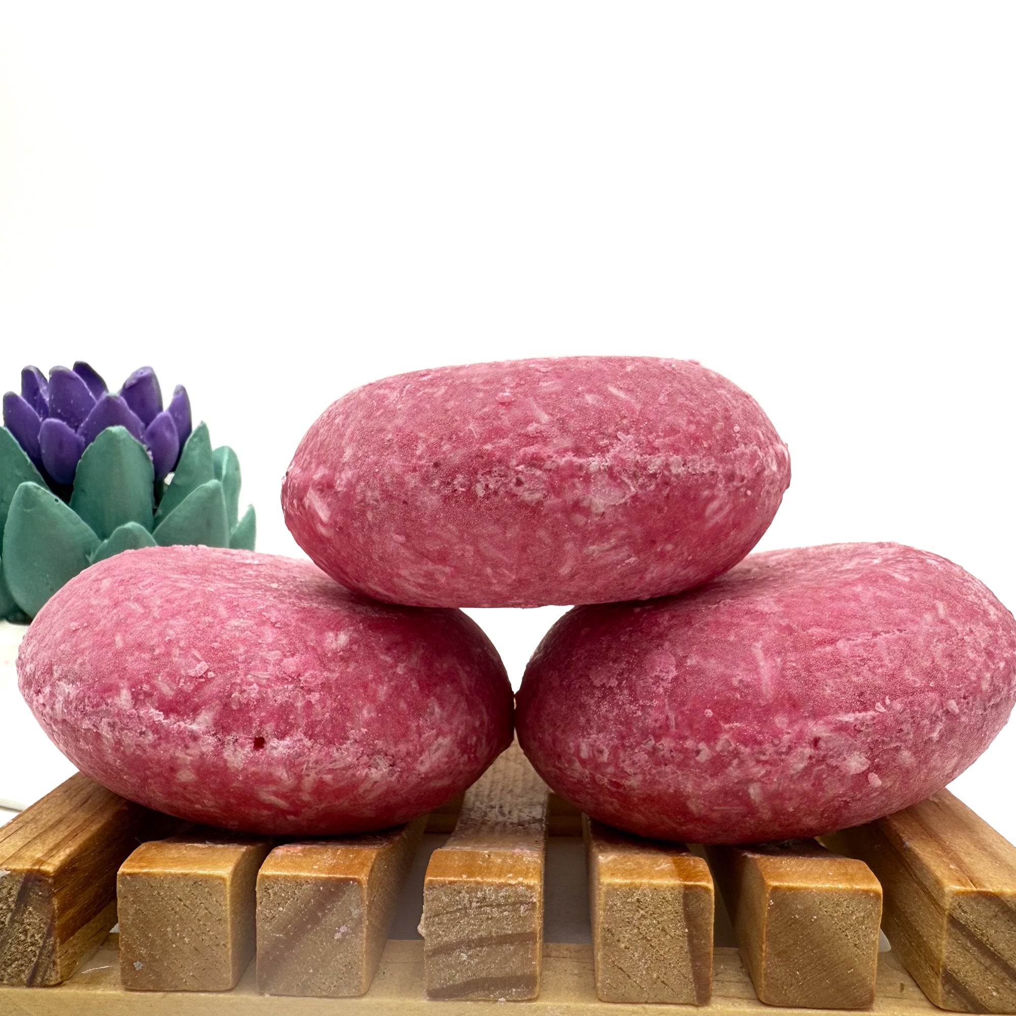 Three beach vibes shampoo bars sitting on. wood soap dish stacked on top of each other.