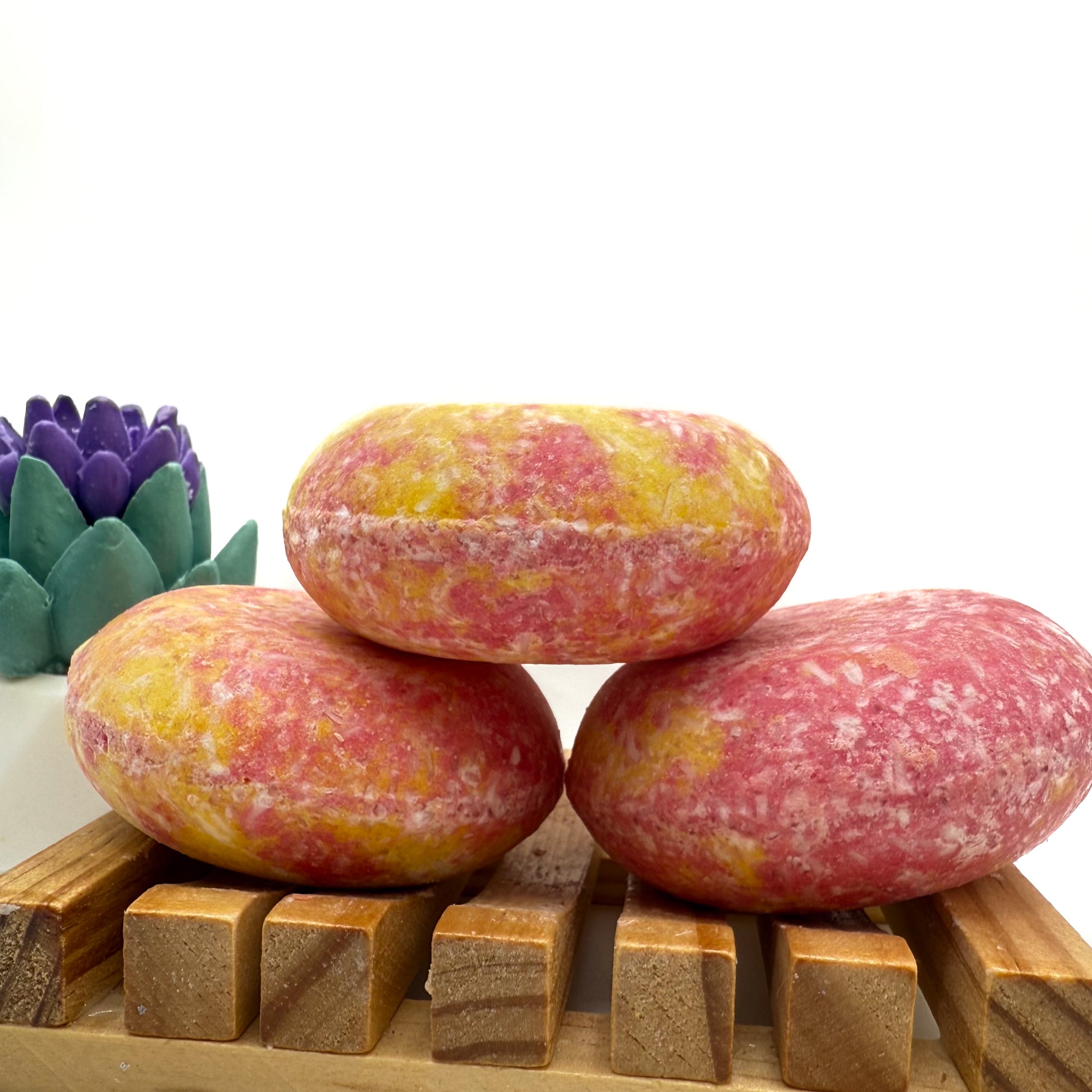 Three Island Hibiscus shampoo bars sitting on. wood soap dish stacked on top of each other.