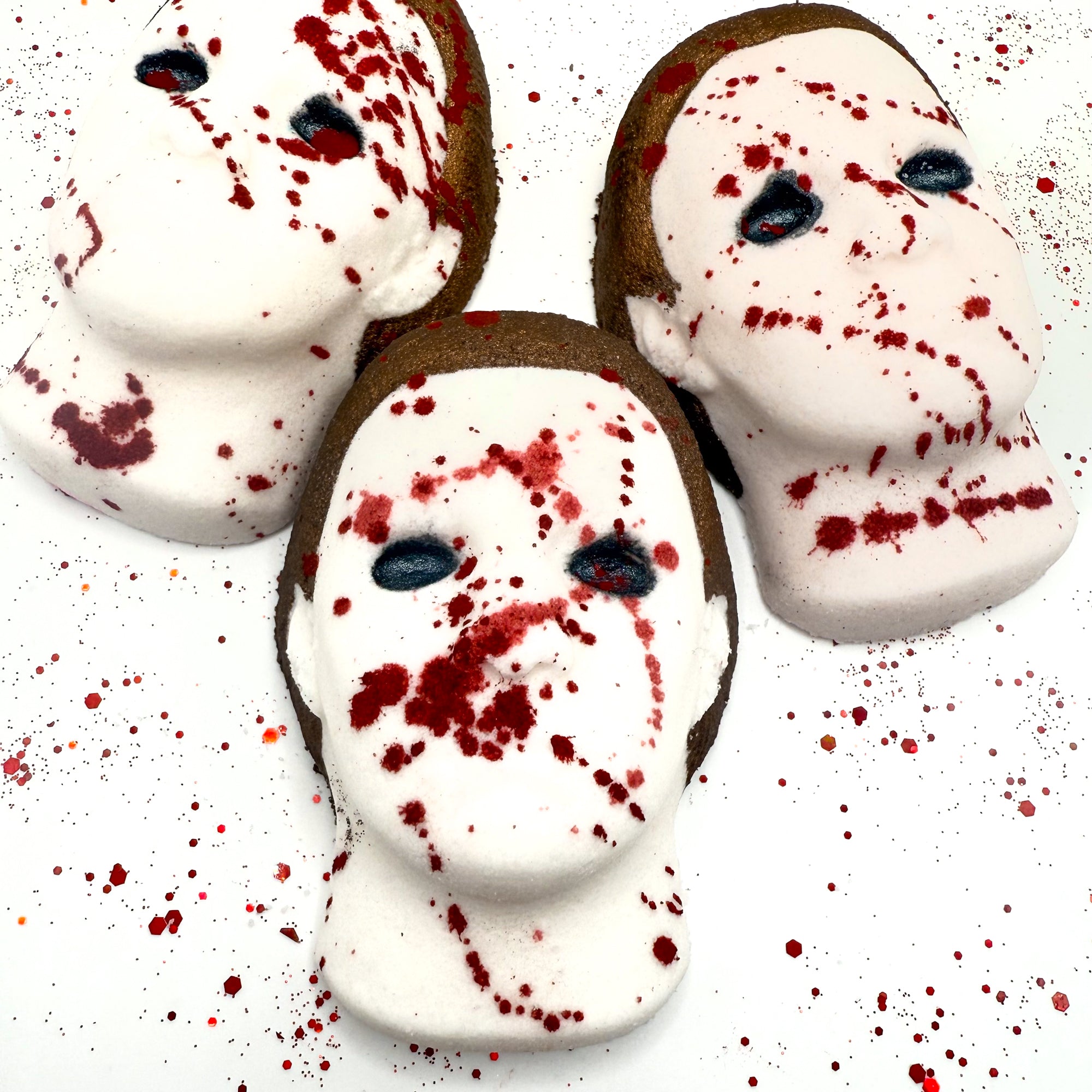 Set of three Silent Stalker bath bombs with white masks, black eyes, and dramatic blood splatter effects. Handmade by Rusted Acre Soap Company.