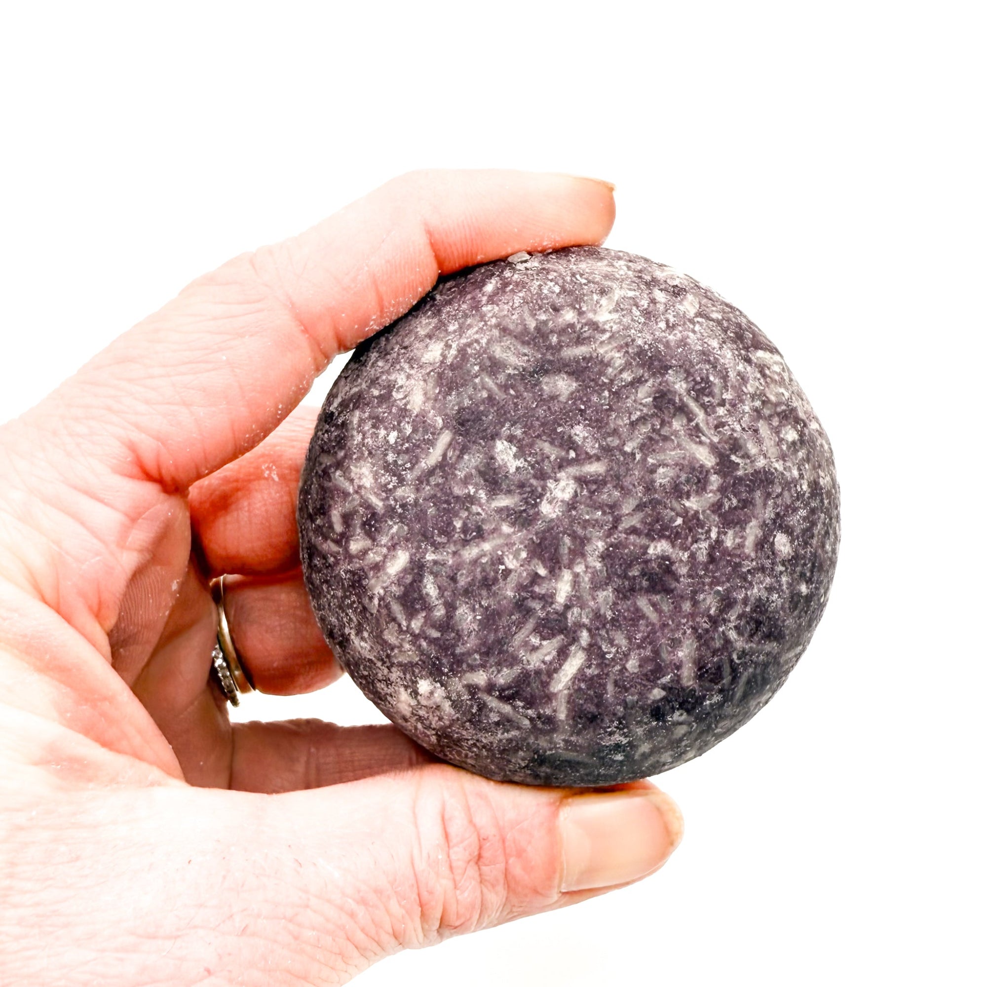 Dark purple eco friendly shampoo bar being held.