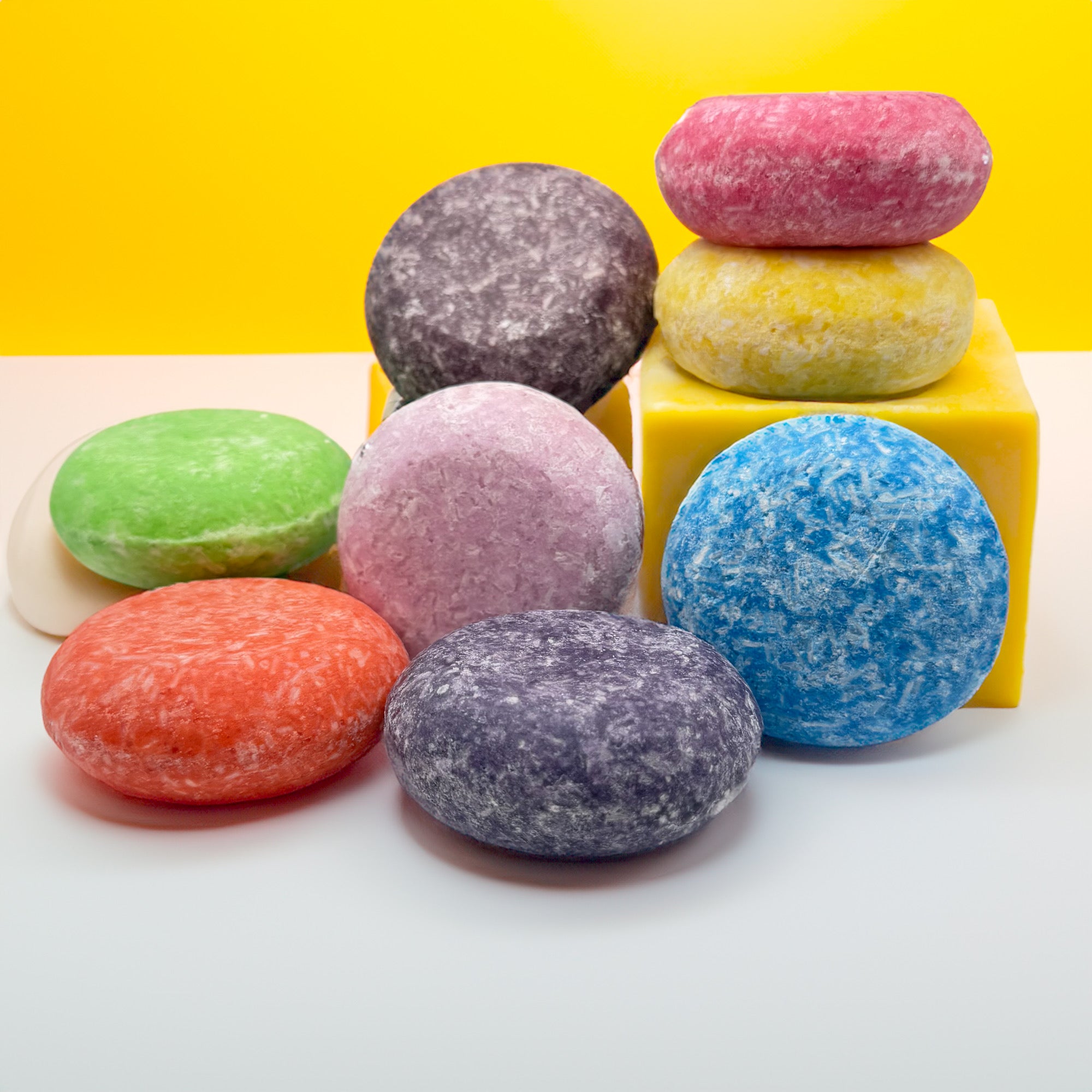 Multiple solid shampoo bars stacked in blocks. Shampoo bars are different colors and made by Rusted Acre Soap Company.