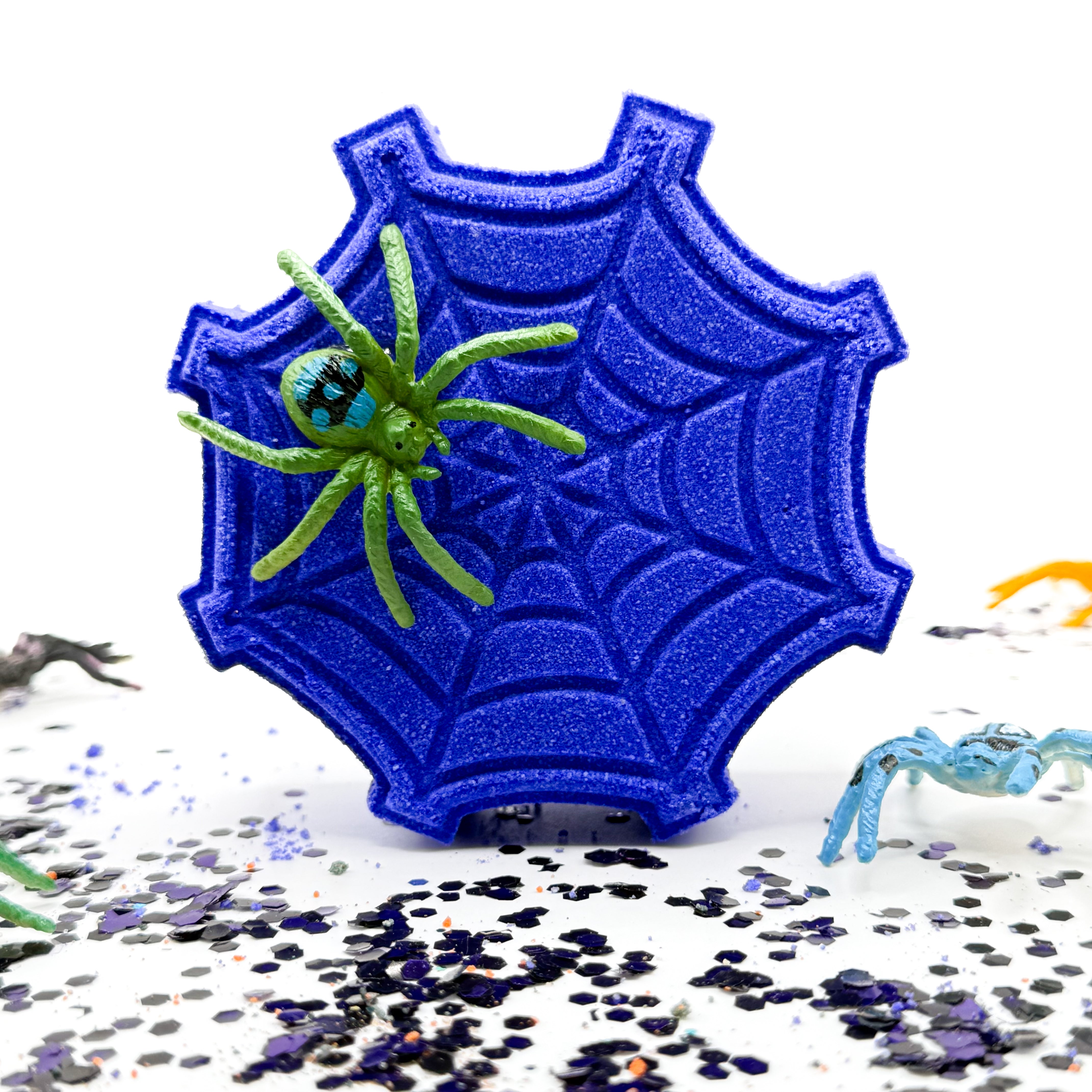 One white spider web shaped bath bomb with a black spider on top