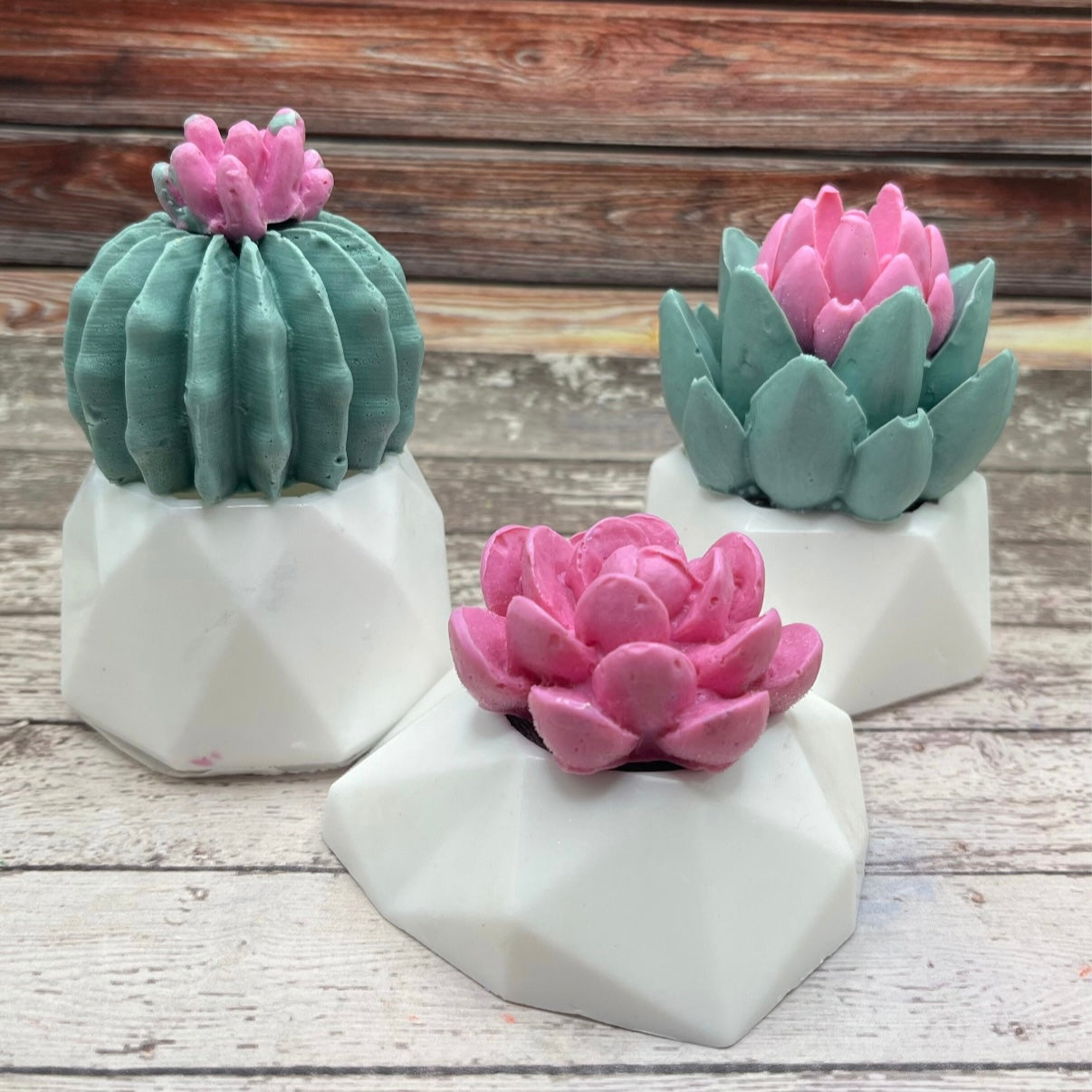 3 green succulent decorative soaps with pink flowers and white flower pots.