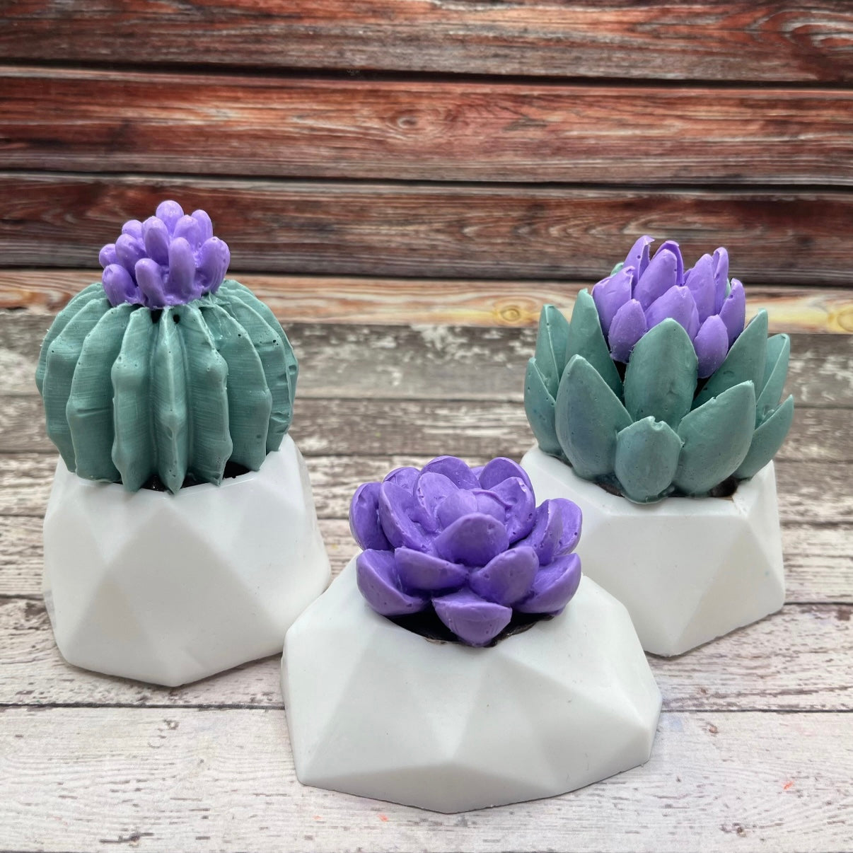 3 decorative succulent soaps with purple flowers and a white flower pot handmade by Rusted Acre Soap Co.