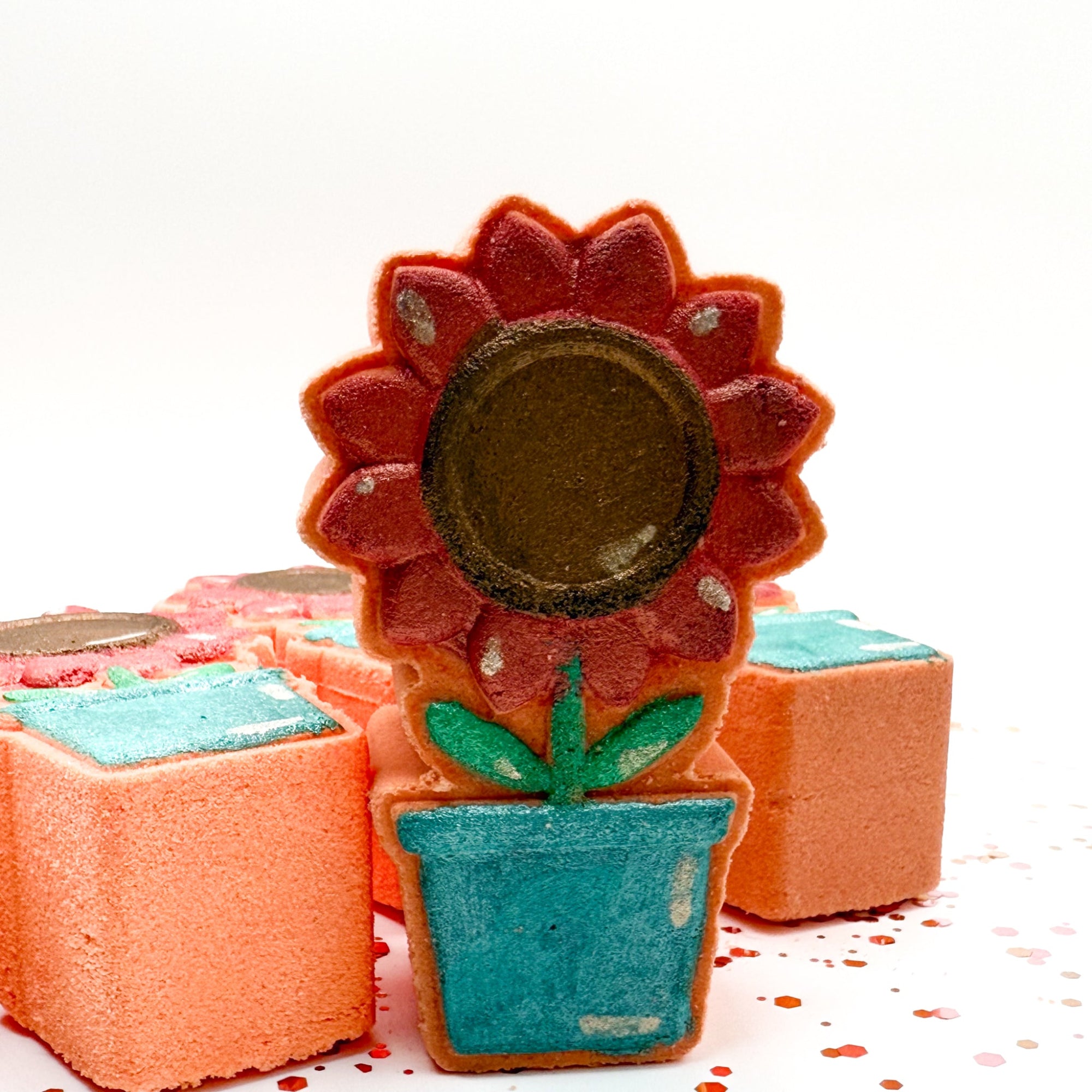 Hand painted Sunflower Pot bath bomb made by Rusted Acre Soap Company. Peach in color with a. pink/coral sunflower. One sunflower pot standing up with up close view.