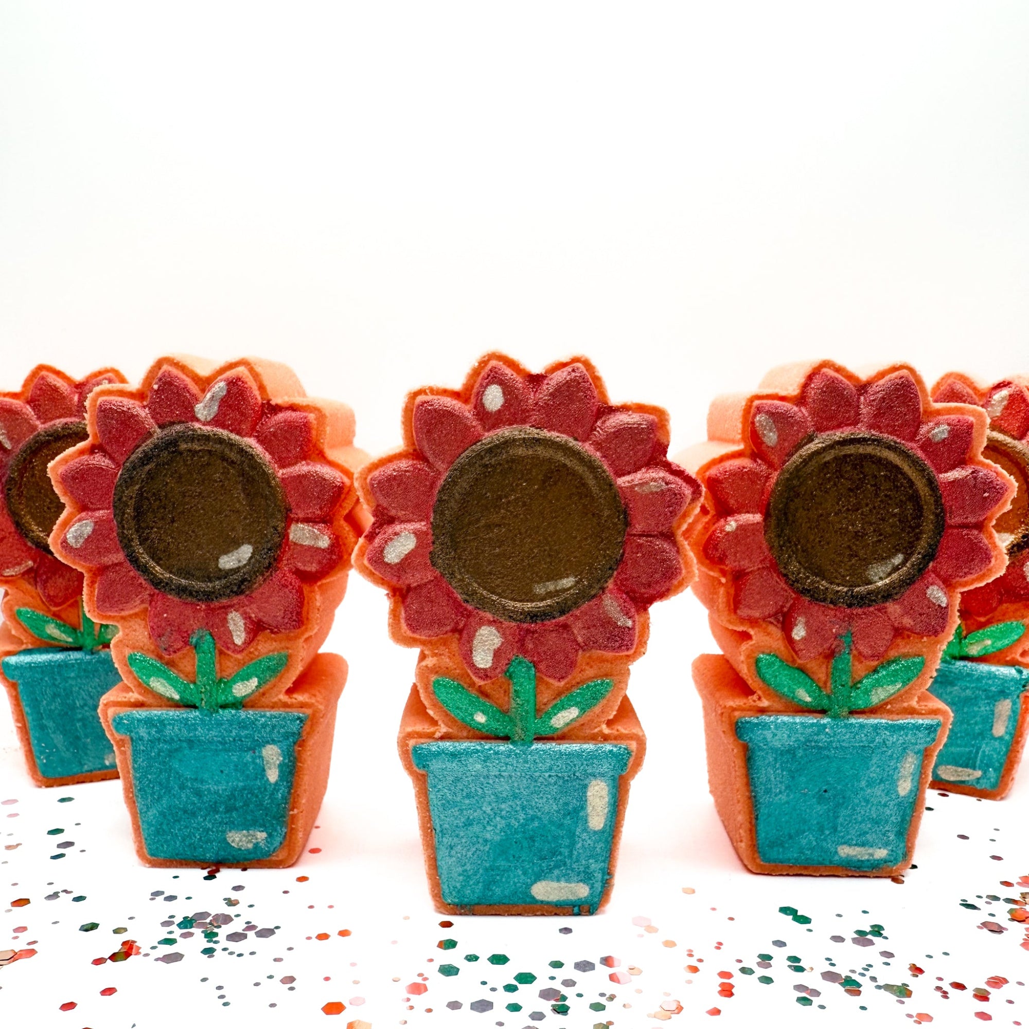 Hand painted Sunflower Pot bath bomb made by Rusted Acre Soap Company. Peach in color with a. pink/coral sunflower. Multiple sunflower pots standing up for a group front view picture.