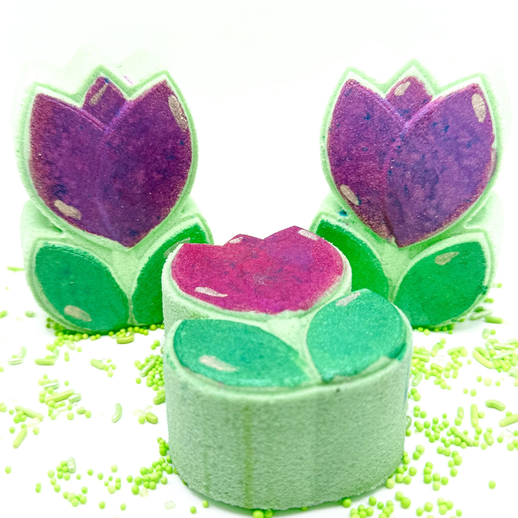Spring Tulip bath bomb, hand painted and made by Rusted Acre Soap Co. Green and pink/purple hand painted tulip bath bombs two standing one laying down.