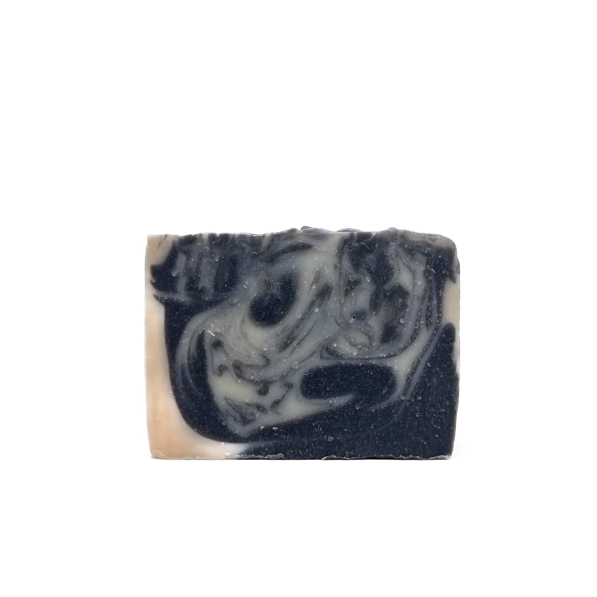 A bar of Rusted Acre Soap Company's Tuxedo handmade soap. Colored charcoal black and natural white swirled.