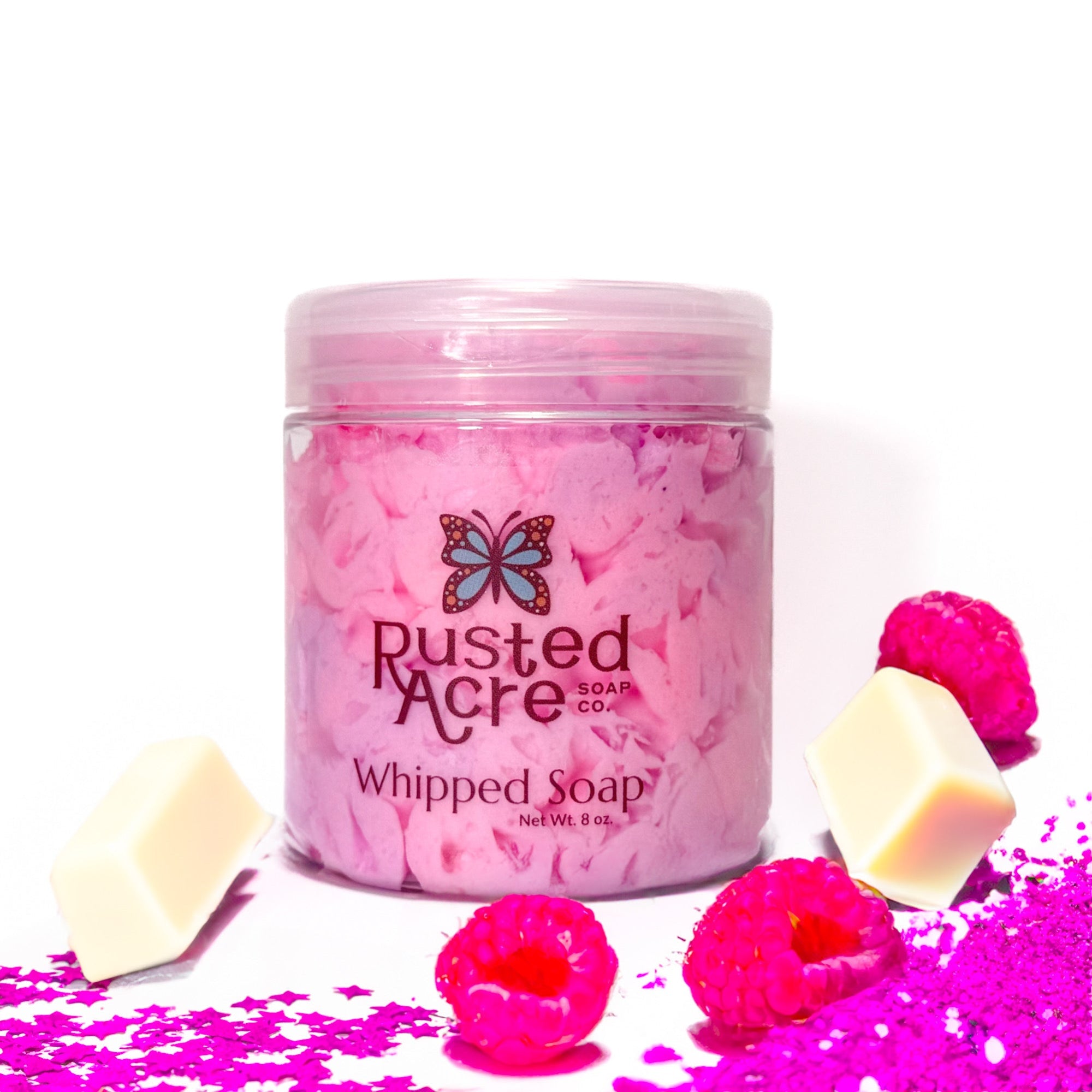 Jar of Rusted Acre Soap Company's vegan unicorn hot chocolate whipped soap. Pink soap in a reusable plastic jar in a lifestyle setting.