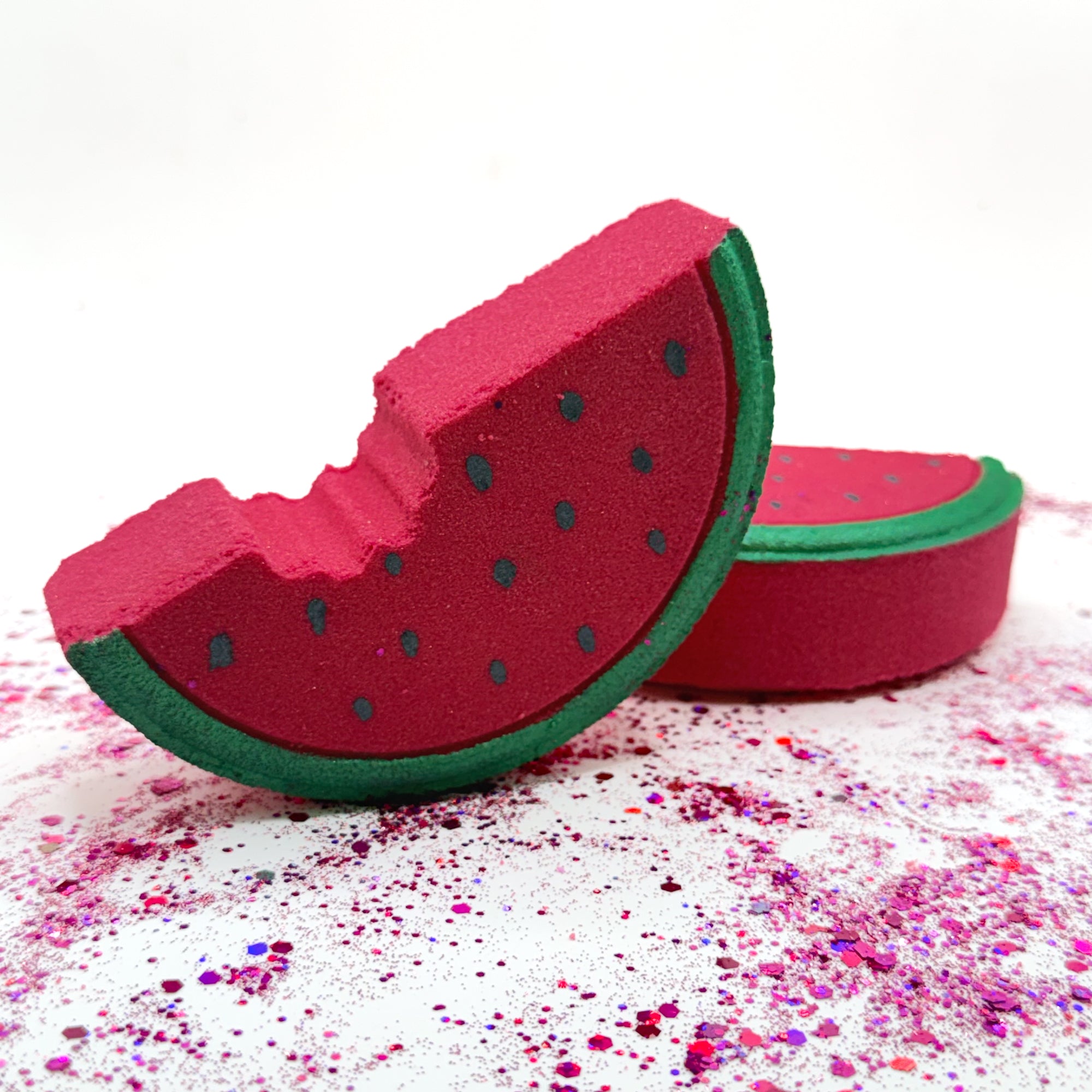 Two hand painted watermelon bath bombs with red and green colors on a white background
